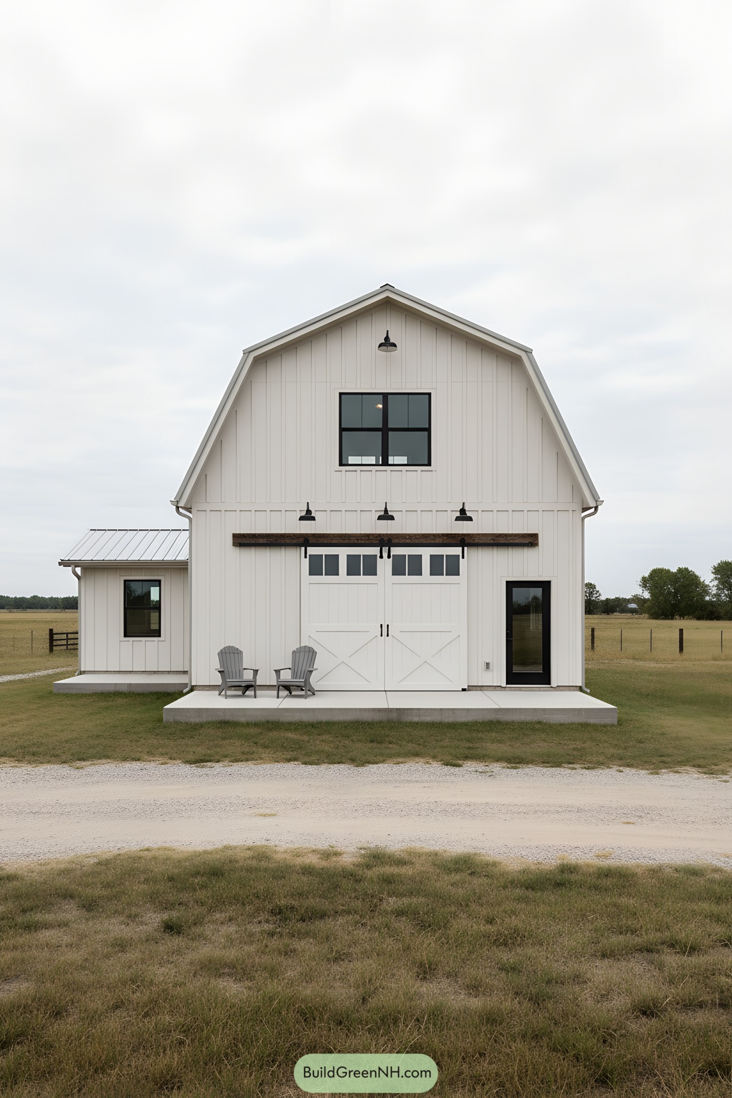 White gambrel barn home with black windows and sliding barn doors
