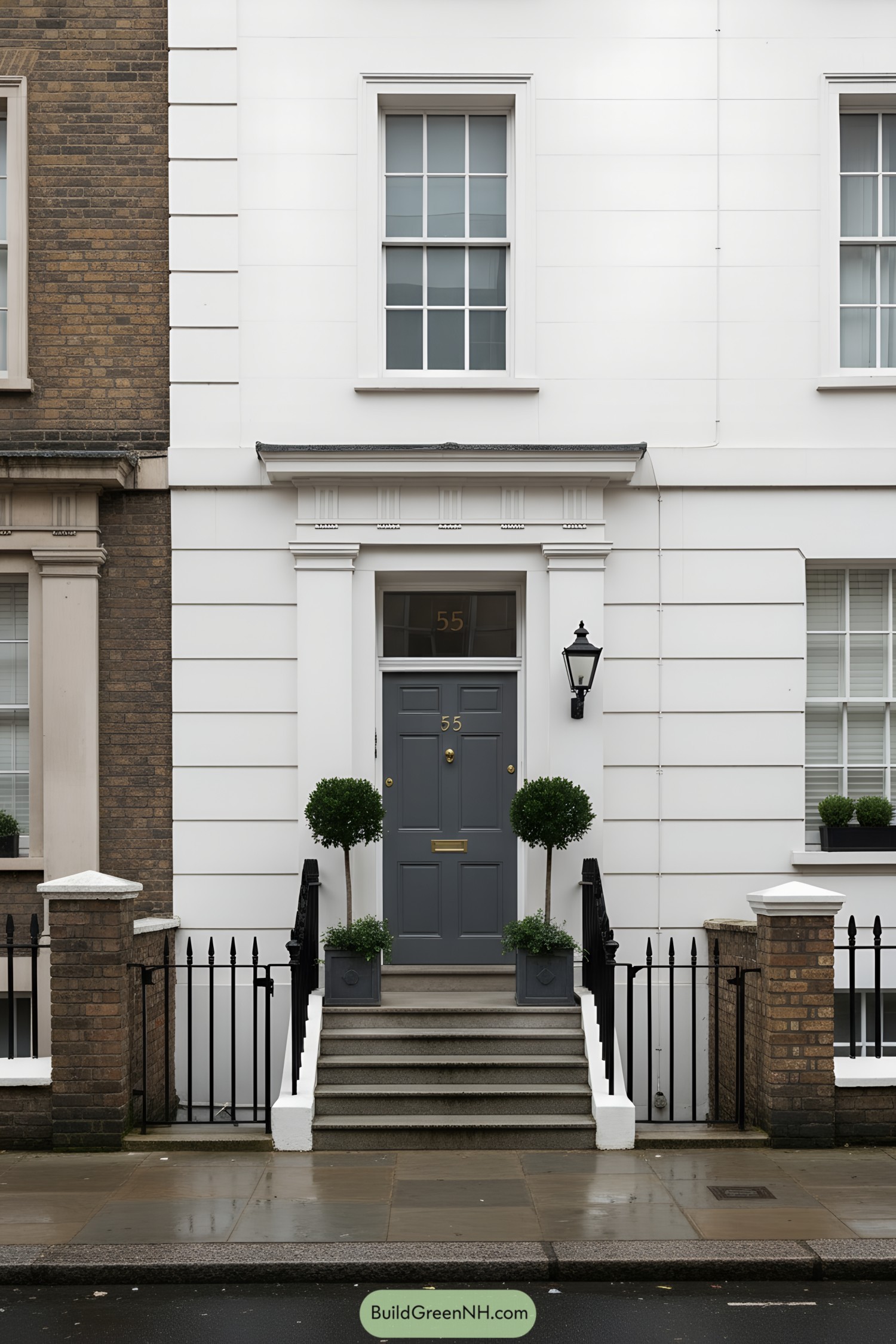White stucco townhouse facade with grey door, steps, and black railings