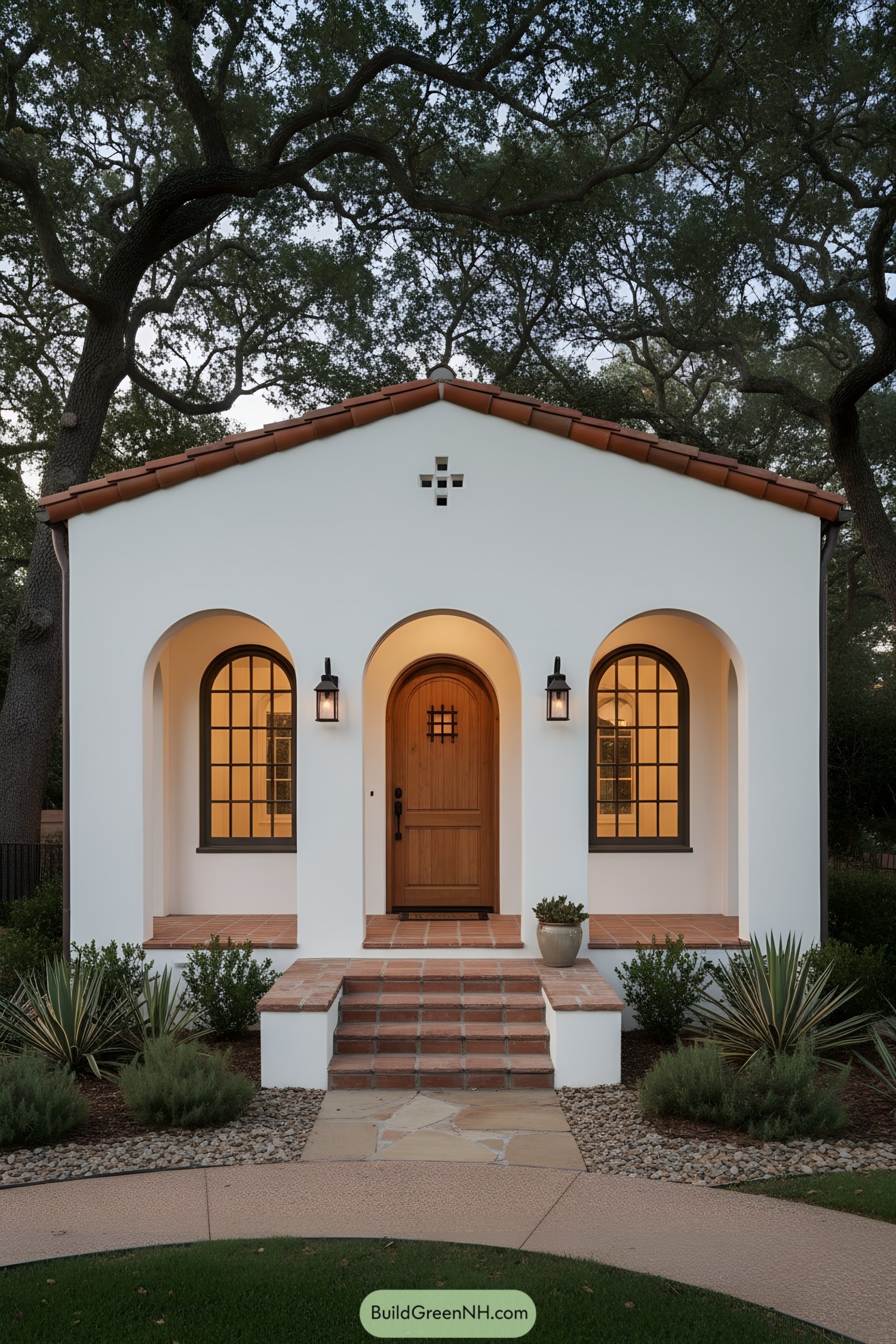 White stucco bungalow with terracotta roof, triple arches, and wooden arched door