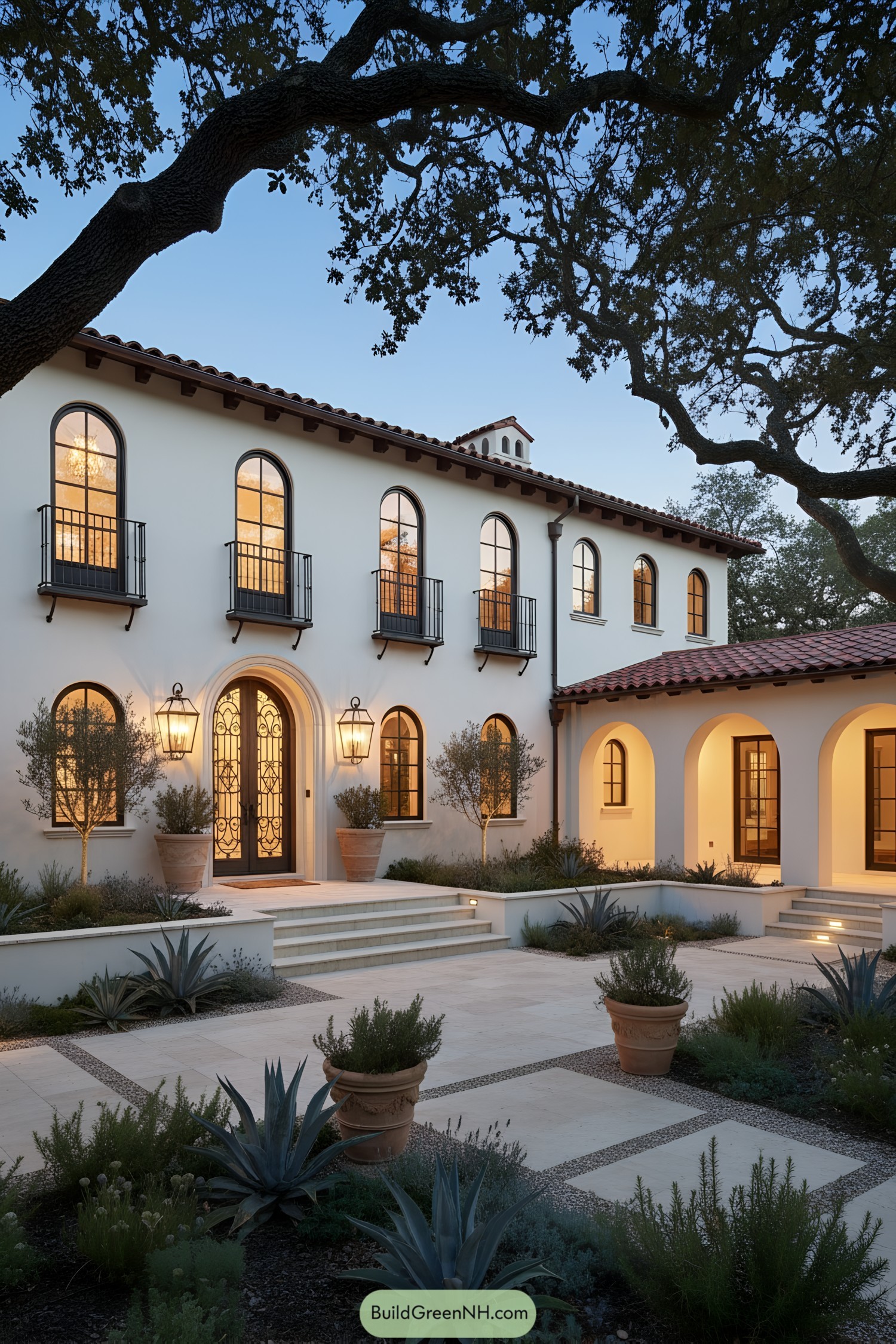 White stucco villa with arches, iron balconies, terracotta roof, and lantern-lit entry