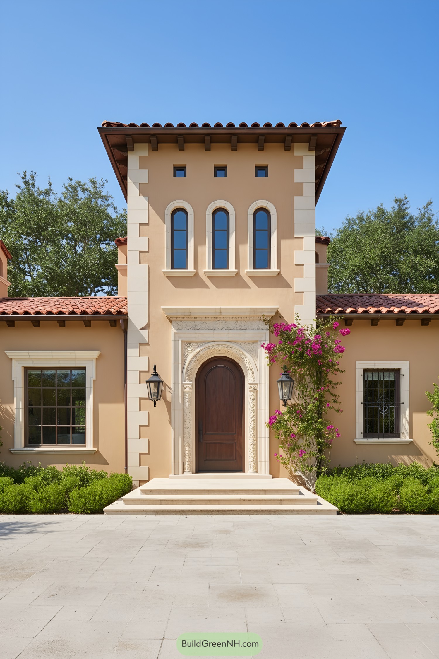 Tall stucco tower with arched door and windows, red tile roof, and bougainvillea