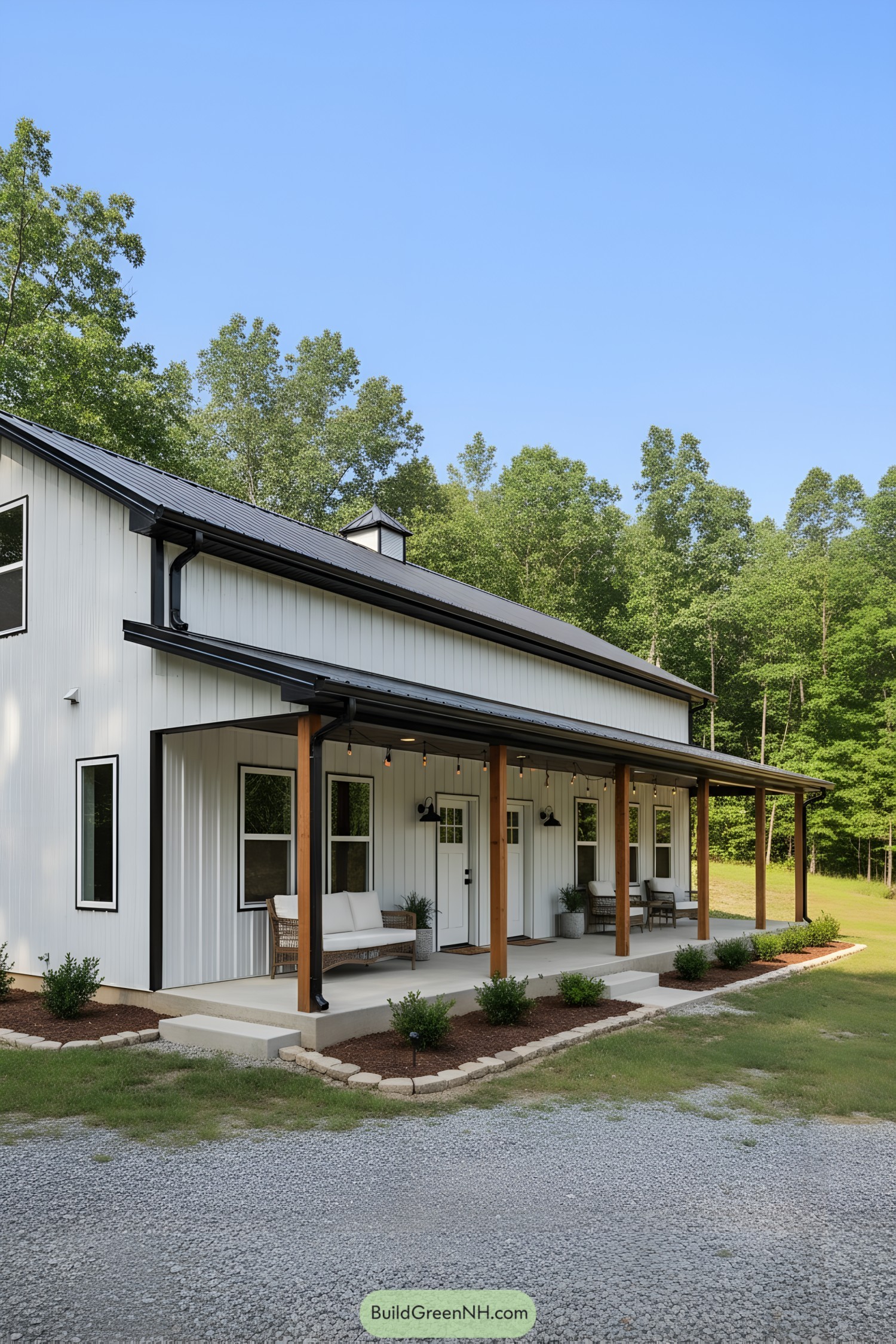 White metal barn home with black roof and wood-post front porch