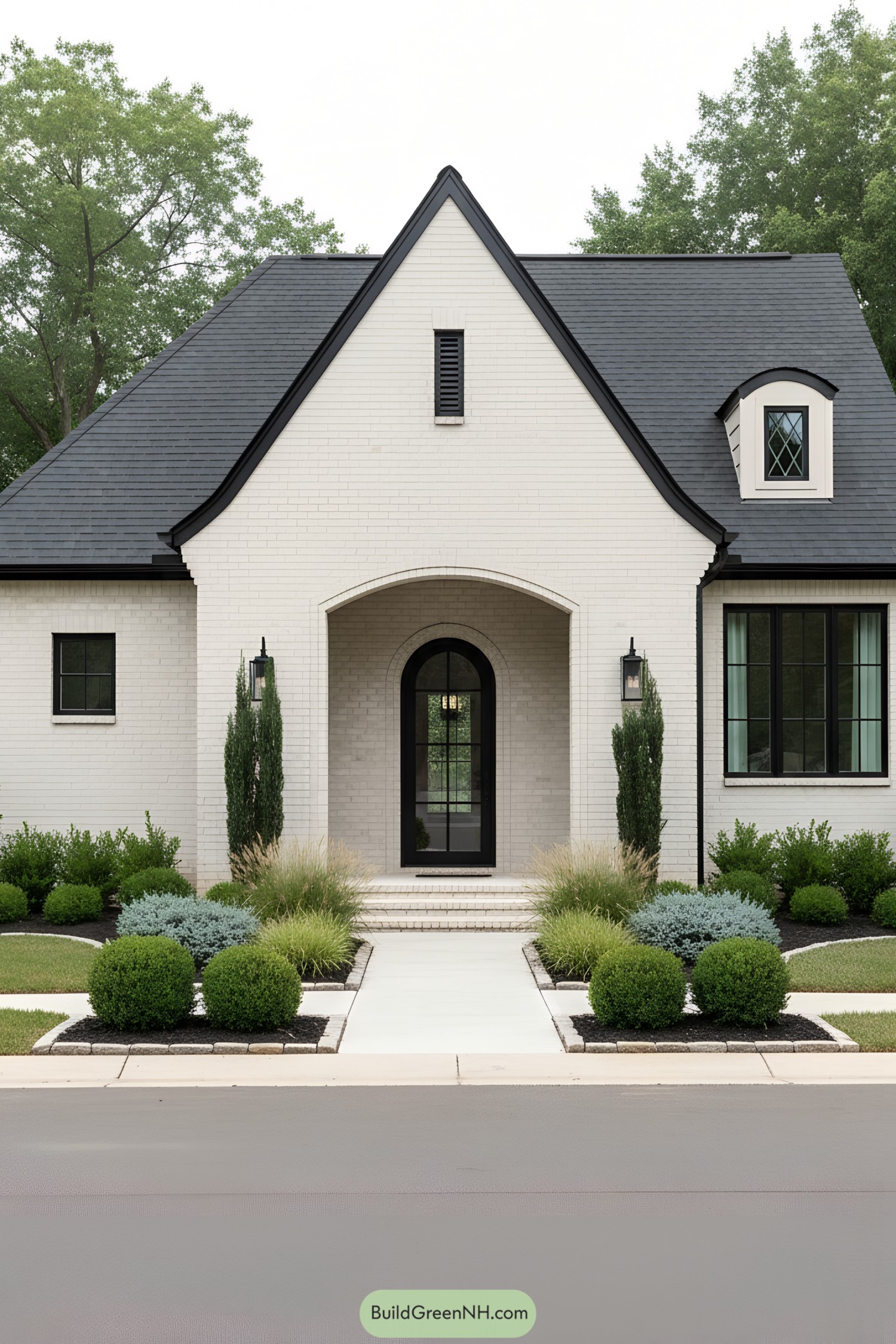 Cream brick modern Tudor with arched steel door and charcoal roof