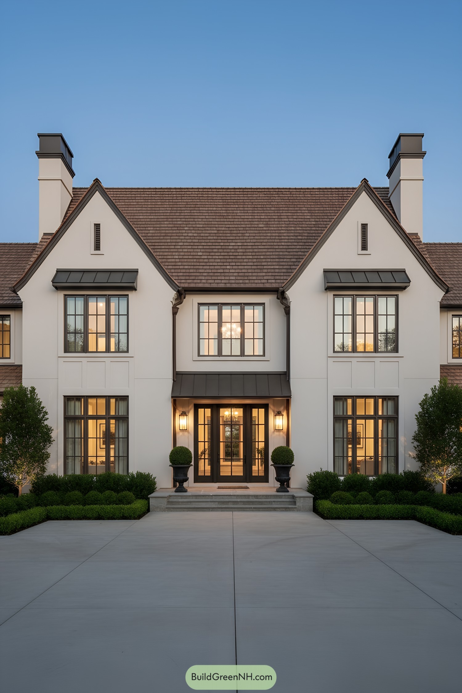 Modern Tudor facade with gables, metal awnings, and warm lighting
