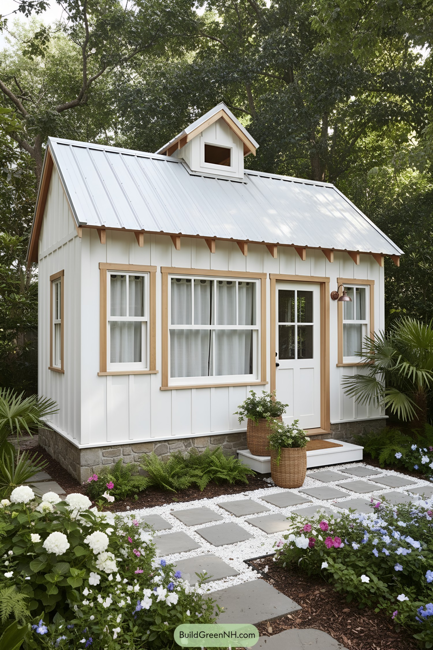 White board-and-batten garden studio with blond trim, metal roof, and dormer