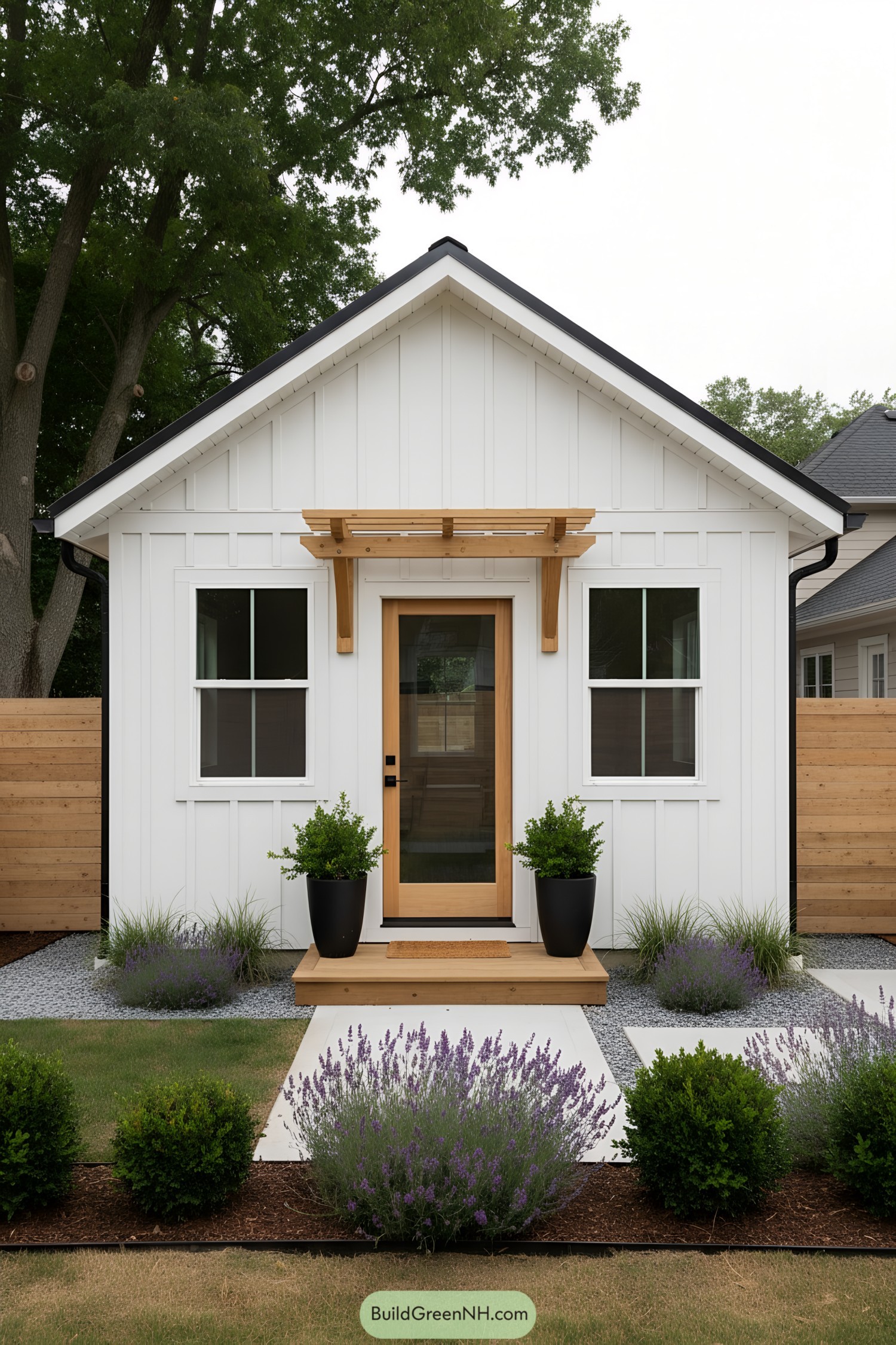 White board-and-batten shed with wood pergola and lavender-lined path