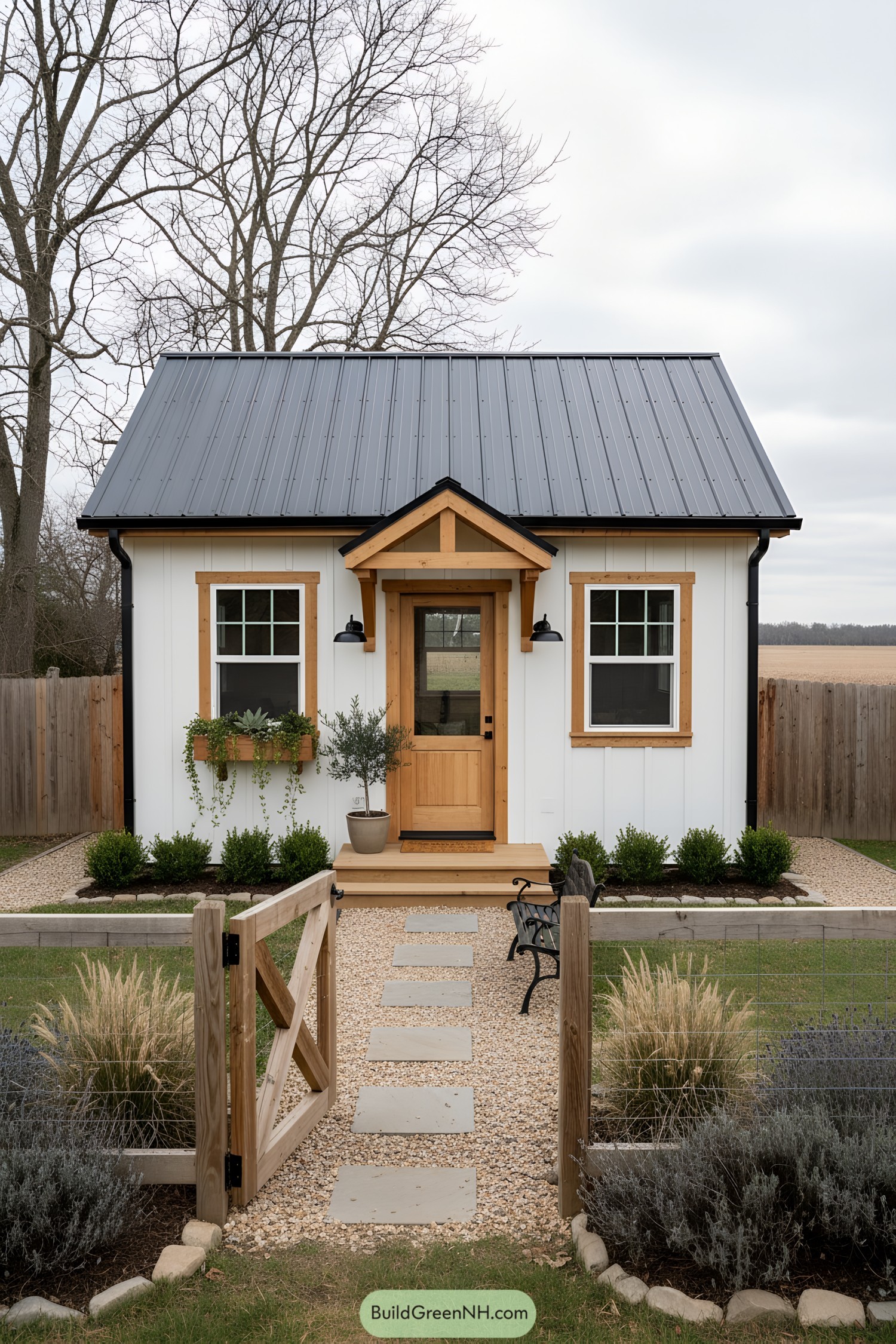 Small white shed with black metal roof, natural wood trim, and tidy gravel path