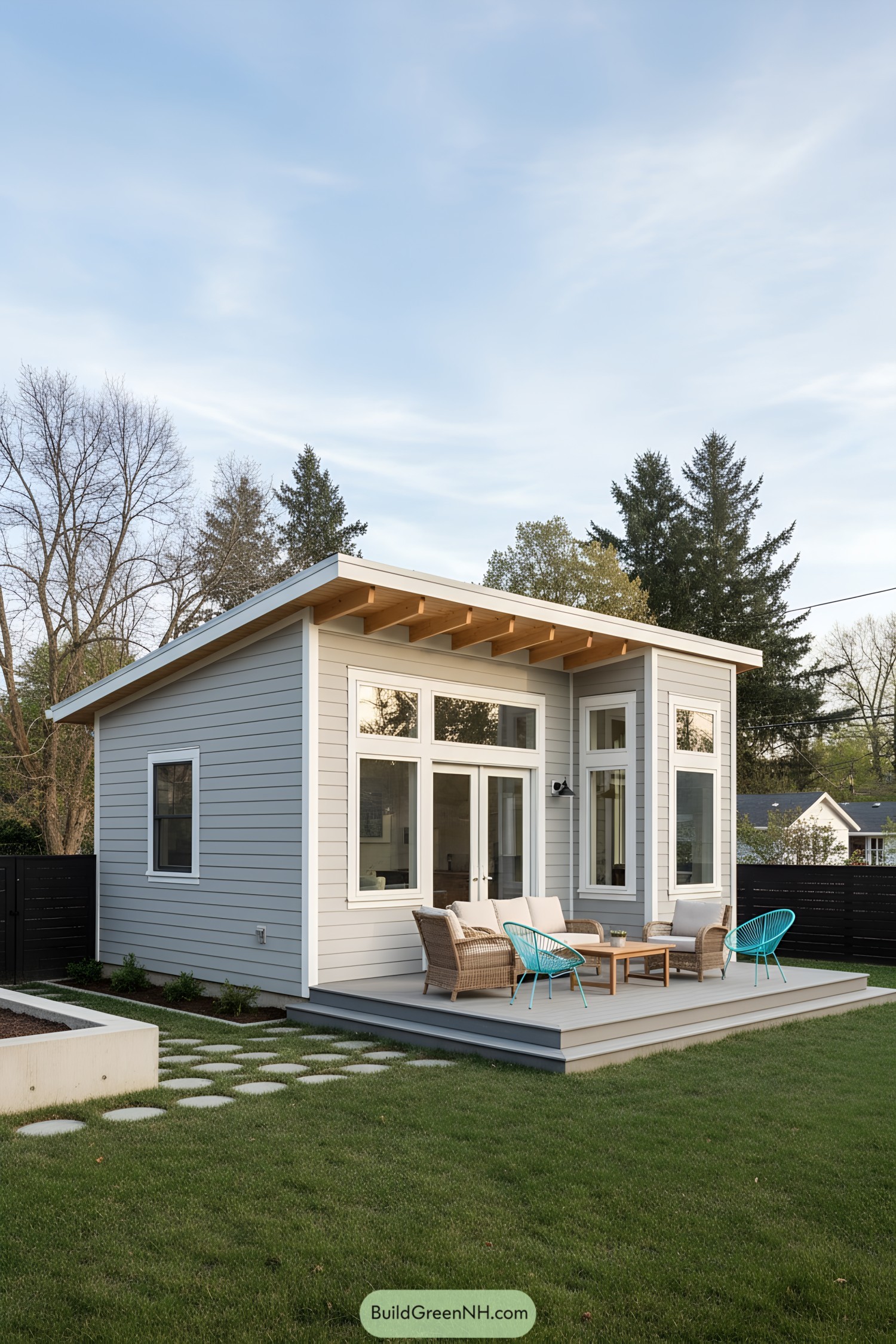 Small modern shed home with sloped roof and tall windows opening to a deck