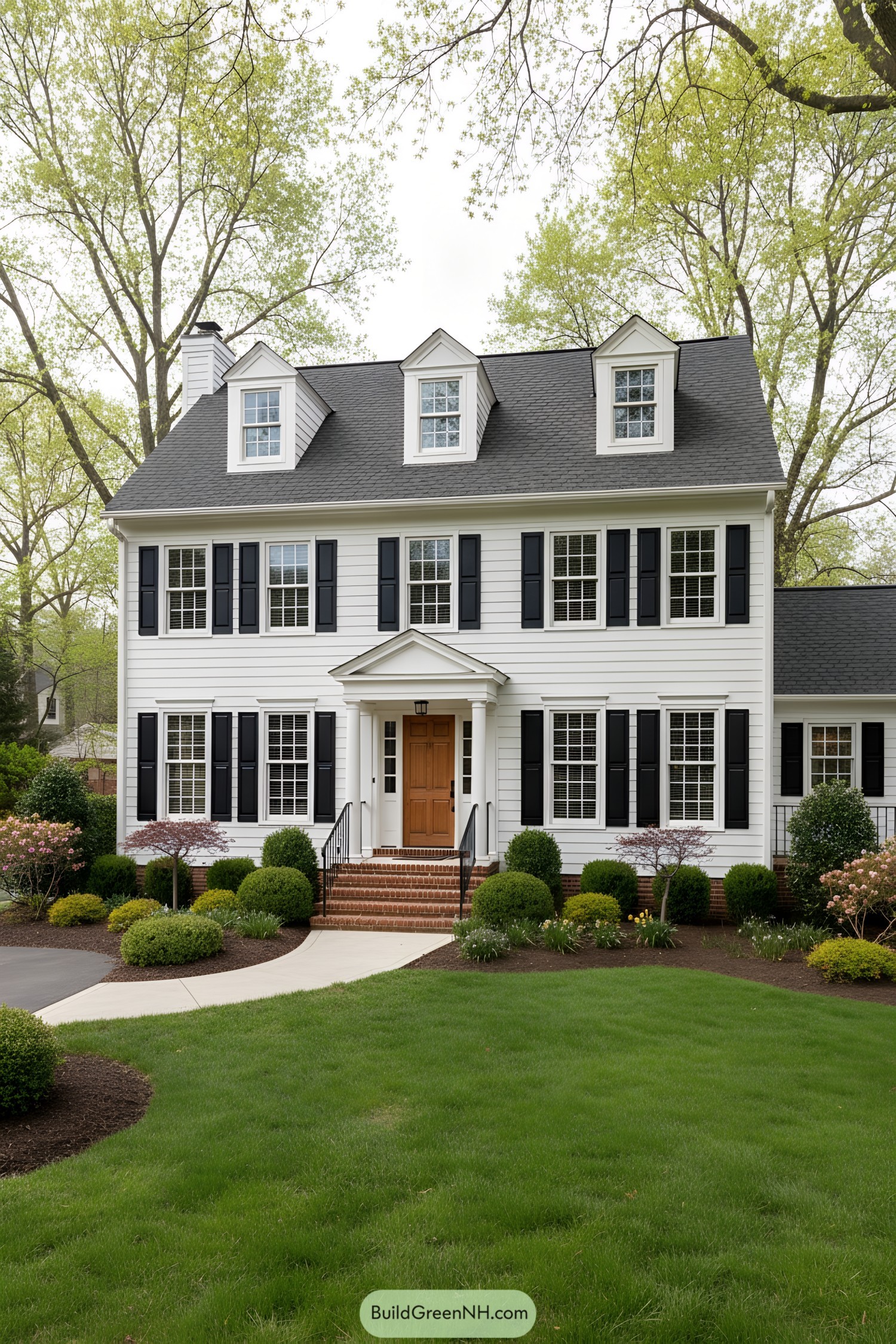 White clapboard colonial with black shutters, brick steps, and three dormers
