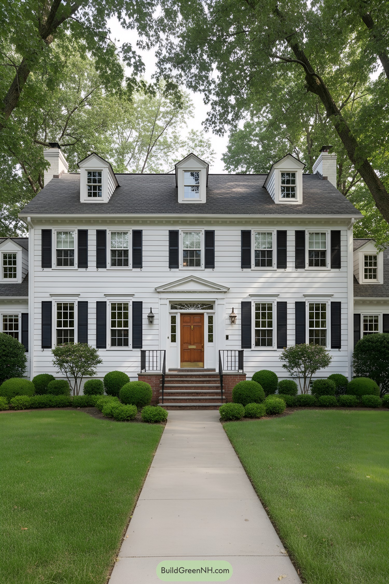 White clapboard colonial with black shutters, dormers, and a wood door centered on a brick stoop