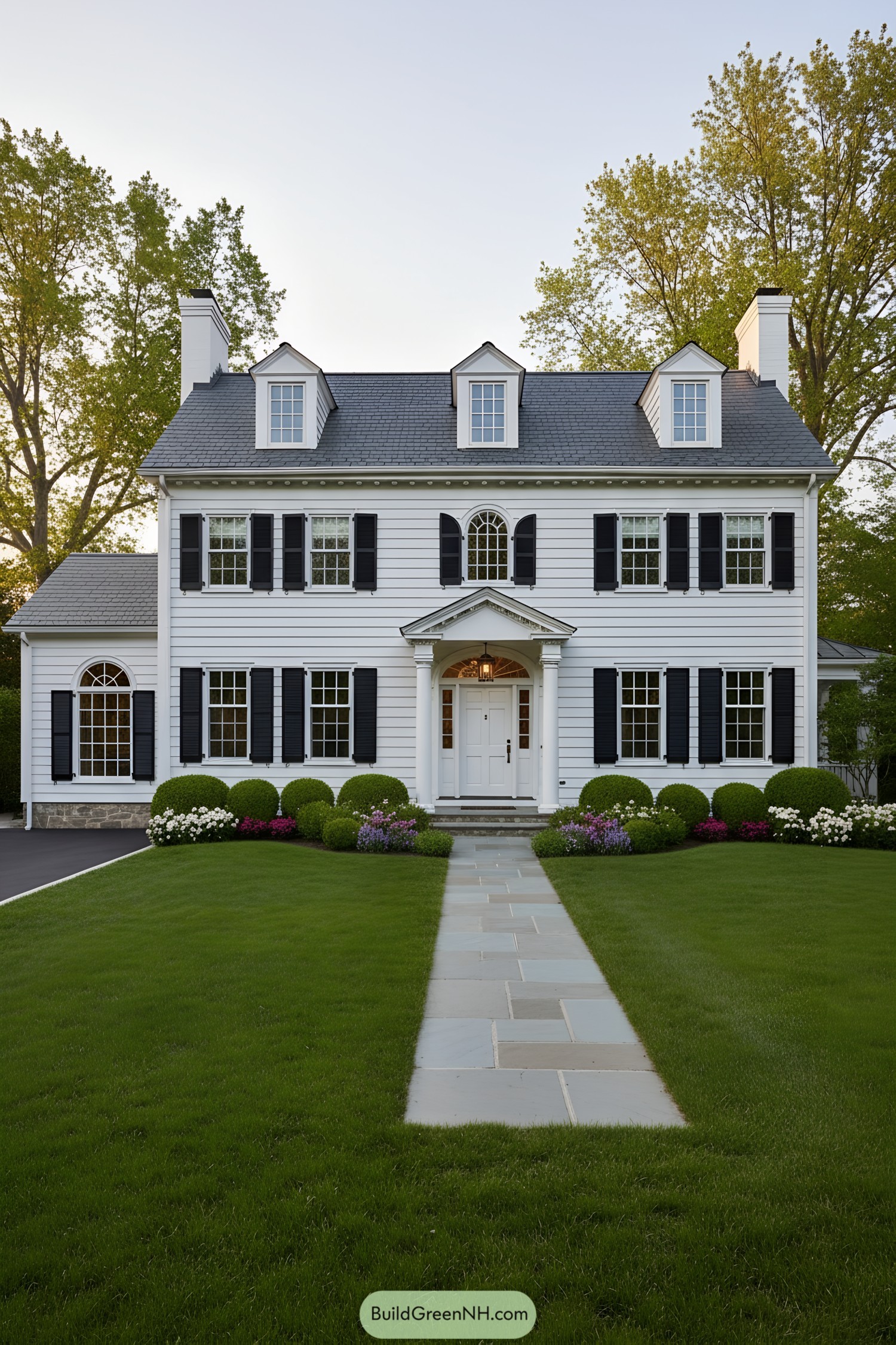 White colonial facade with black shutters, dormers, and pedimented entry