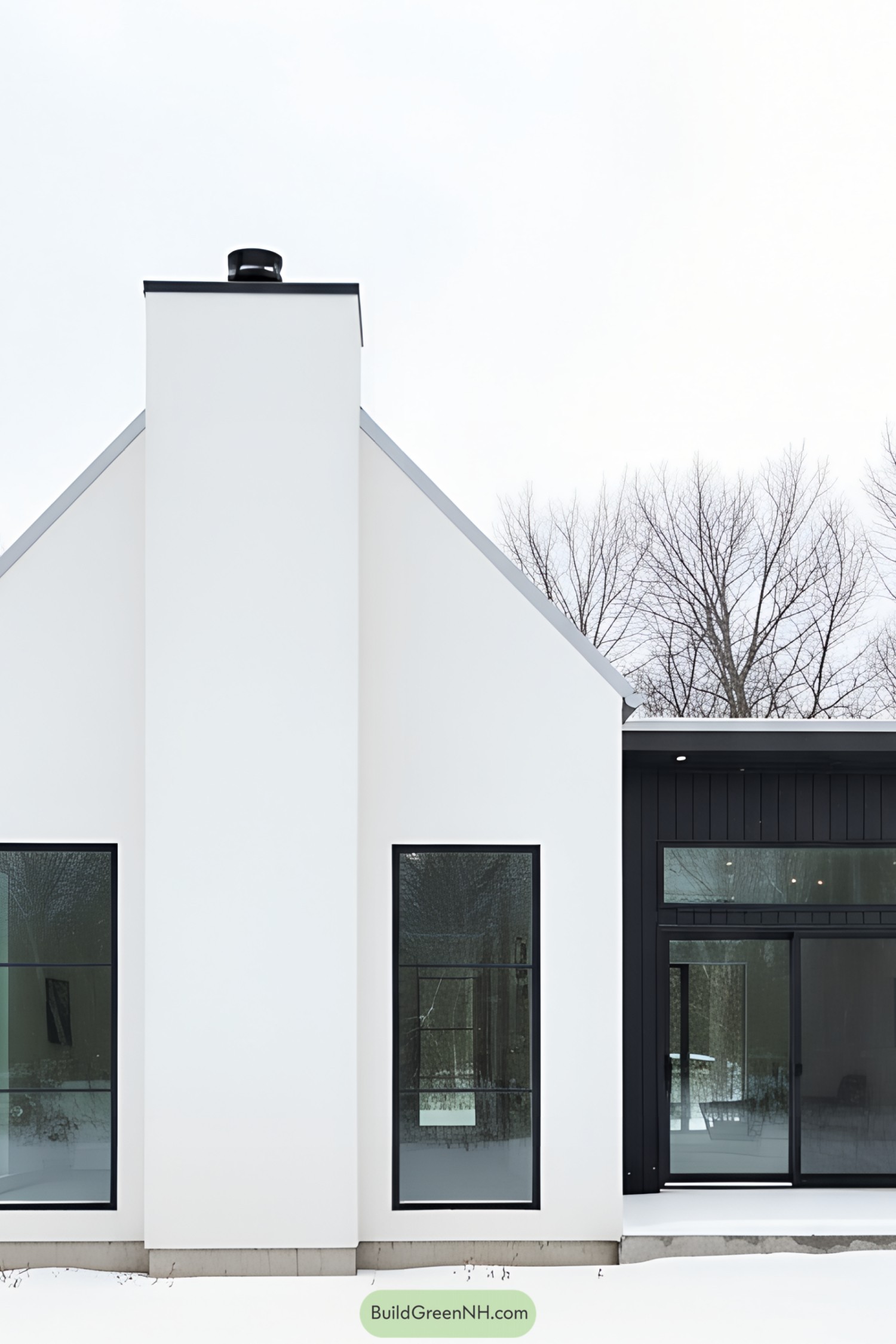 White gabled cottage with tall chimney and charcoal flat-roof wing in snow