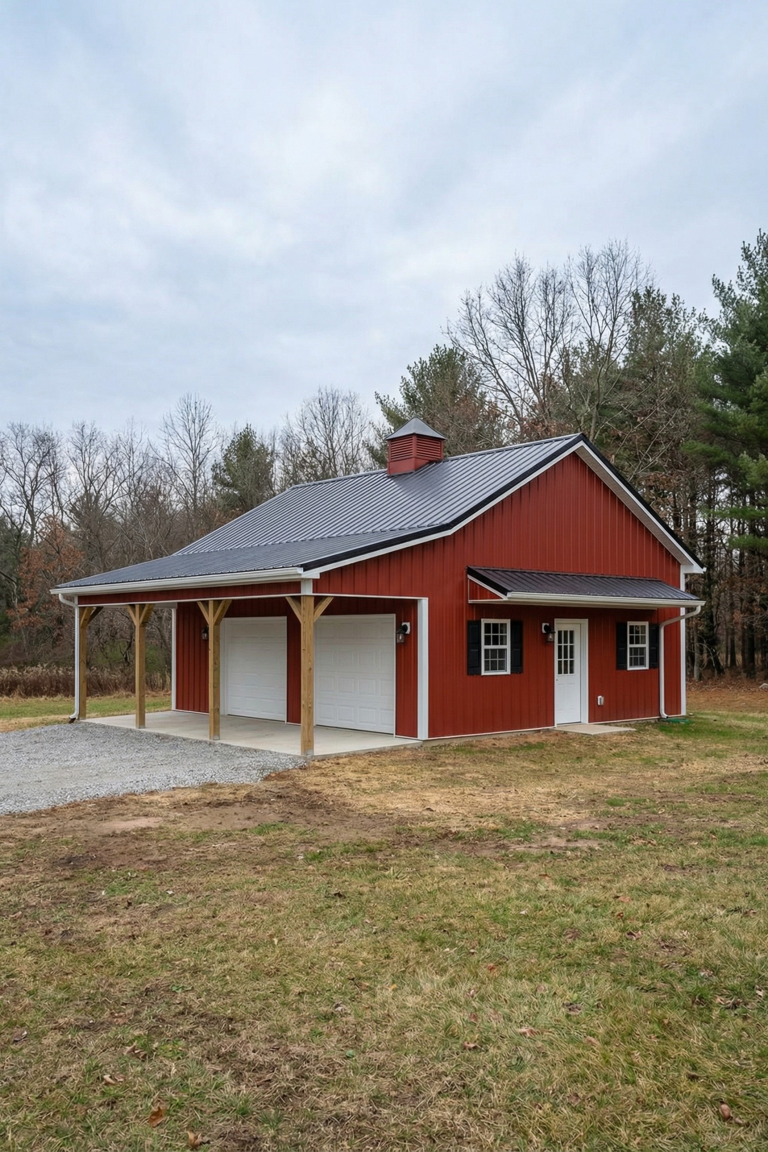 Red barn with metal roof and dual garage bays under a lean-to porch