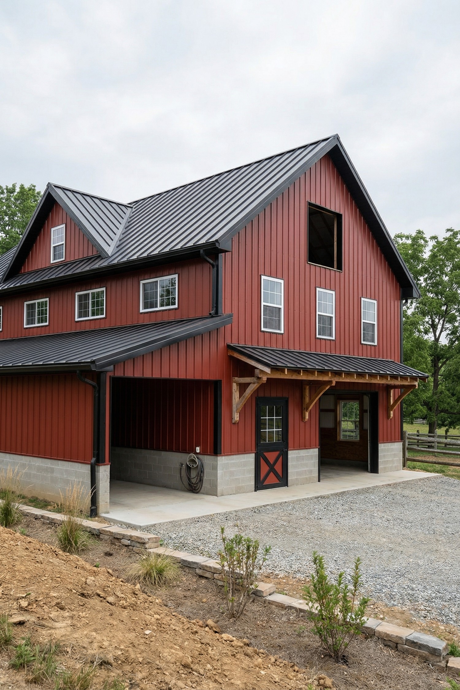 Red barn with black metal roof, timber awning, and dual bays