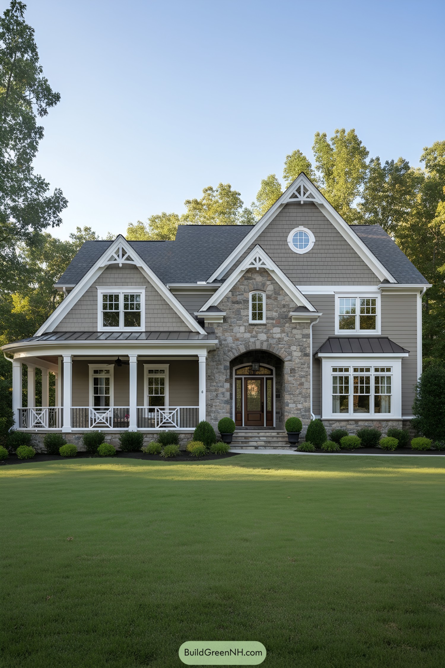 Gray shingle and stone suburban house with wraparound porch and gabled roof