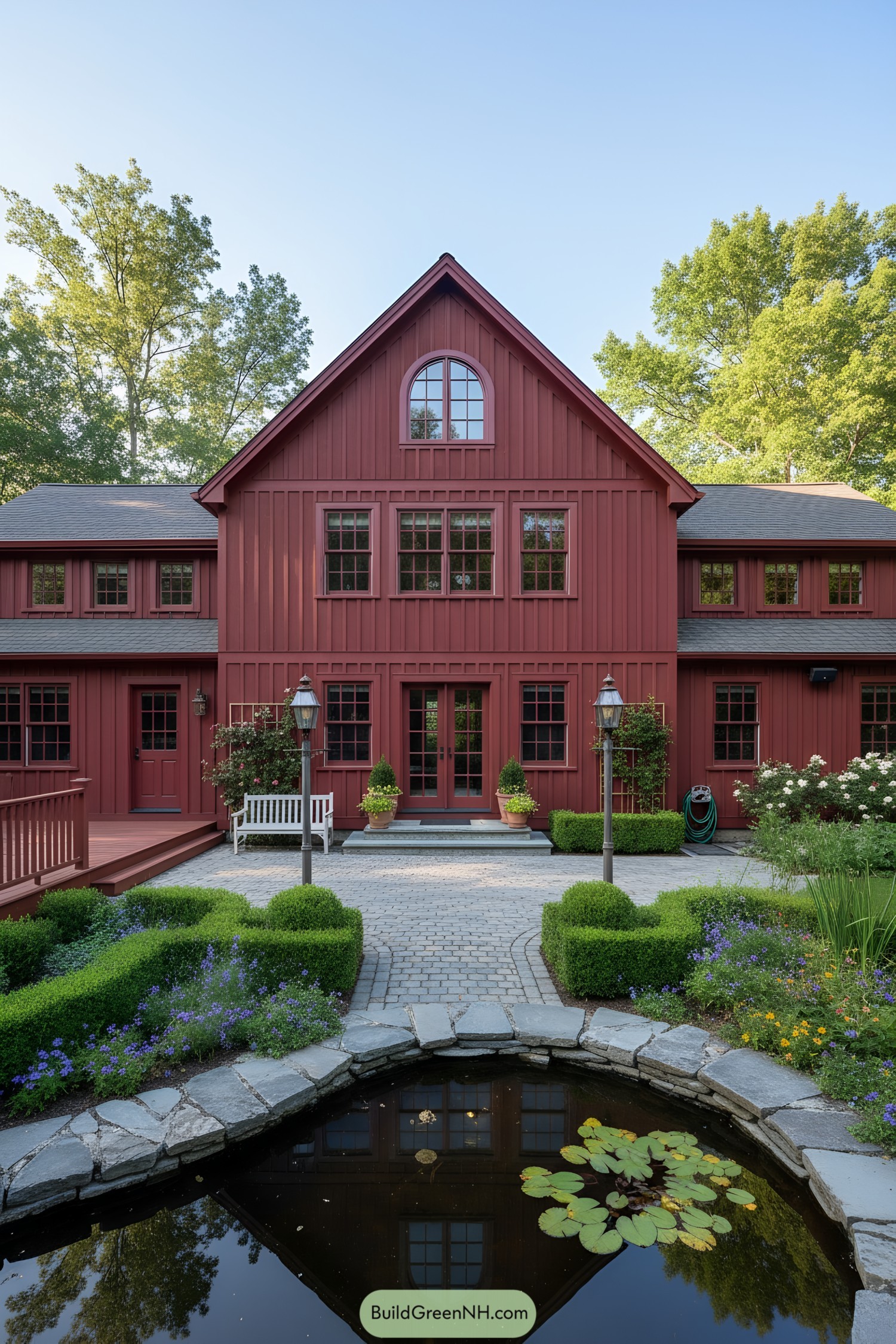 Red board-and-batten barn home with pond and formal garden entry