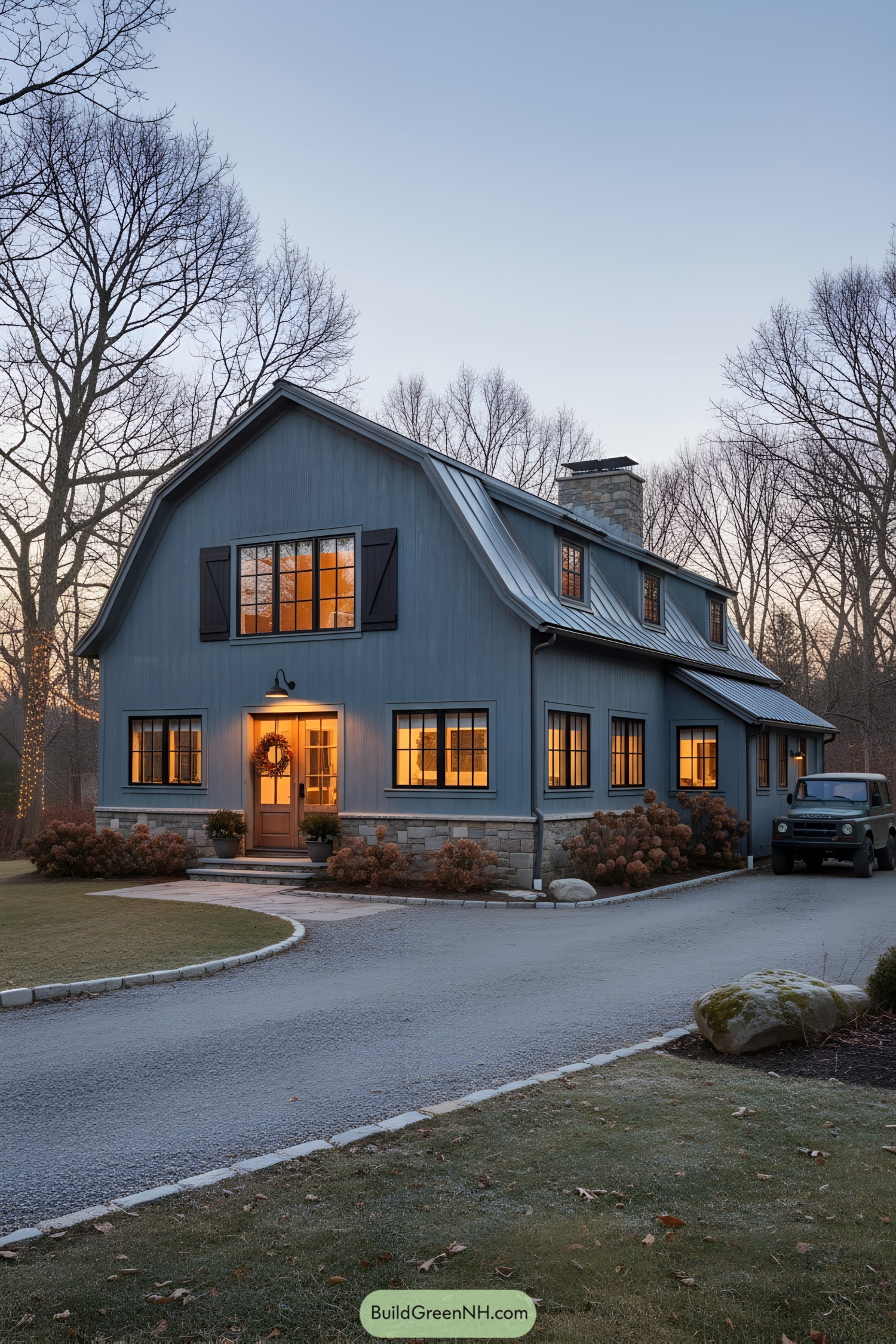 Blue-gray gambrel barn home with warm windows at dusk