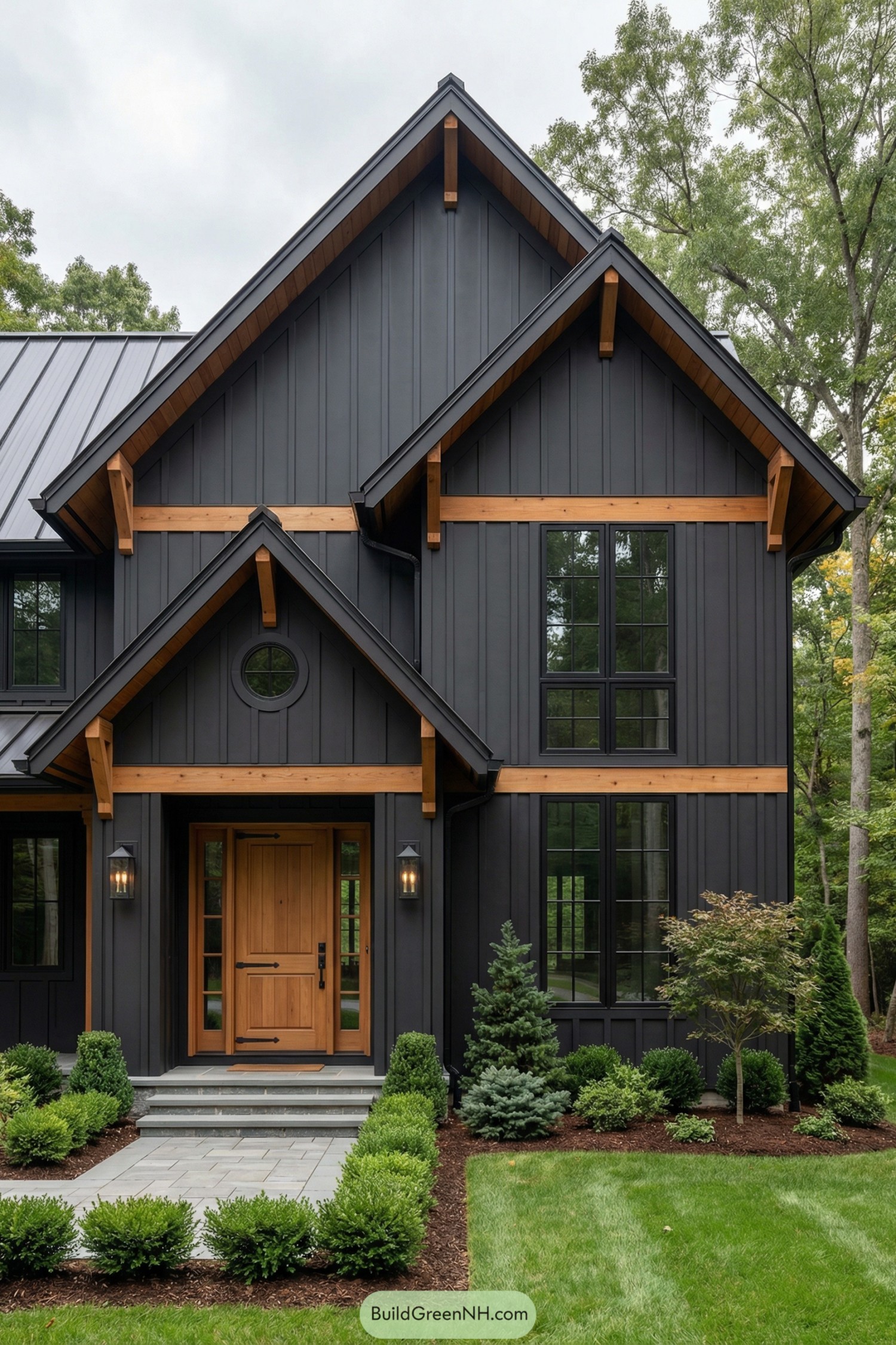 Dark charcoal board-and-batten house with cedar trim, gabled rooflines, and neatly landscaped front entry