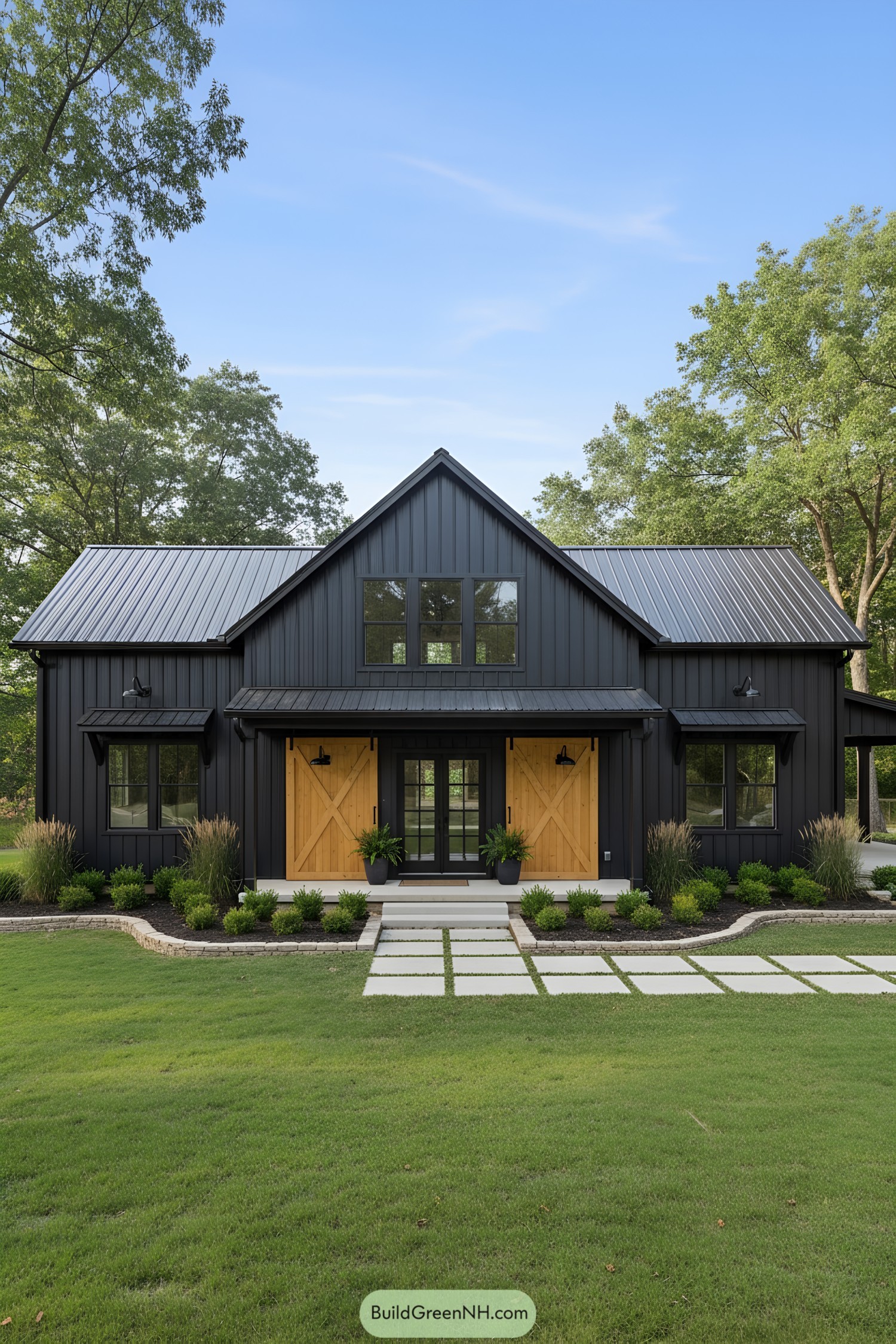 Black board-and-batten barndominium with metal roof, centered gable, and honey-toned sliding barn doors flanking a glass entry