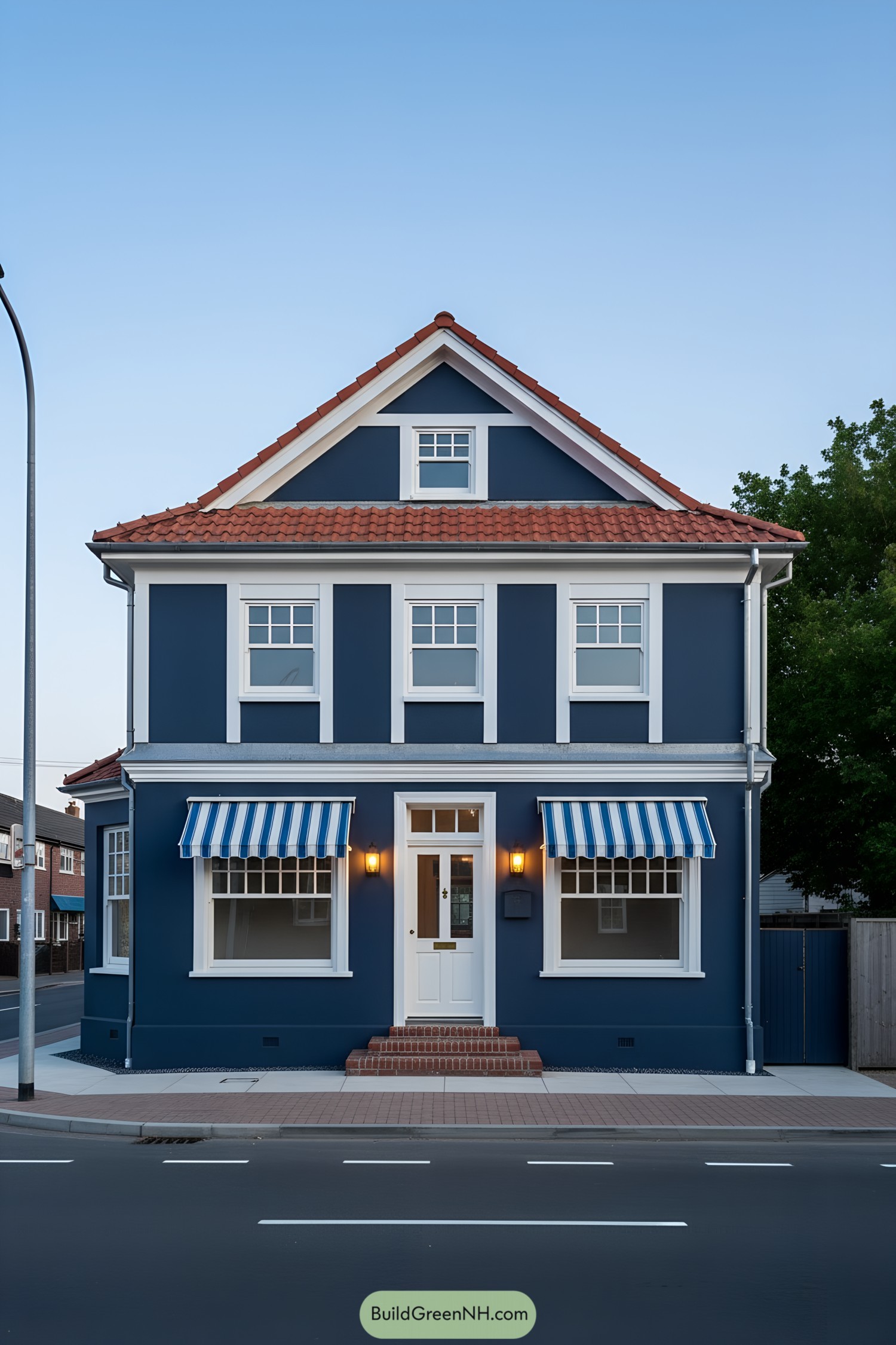 Navy two-story home with white trim and blue‑striped awnings