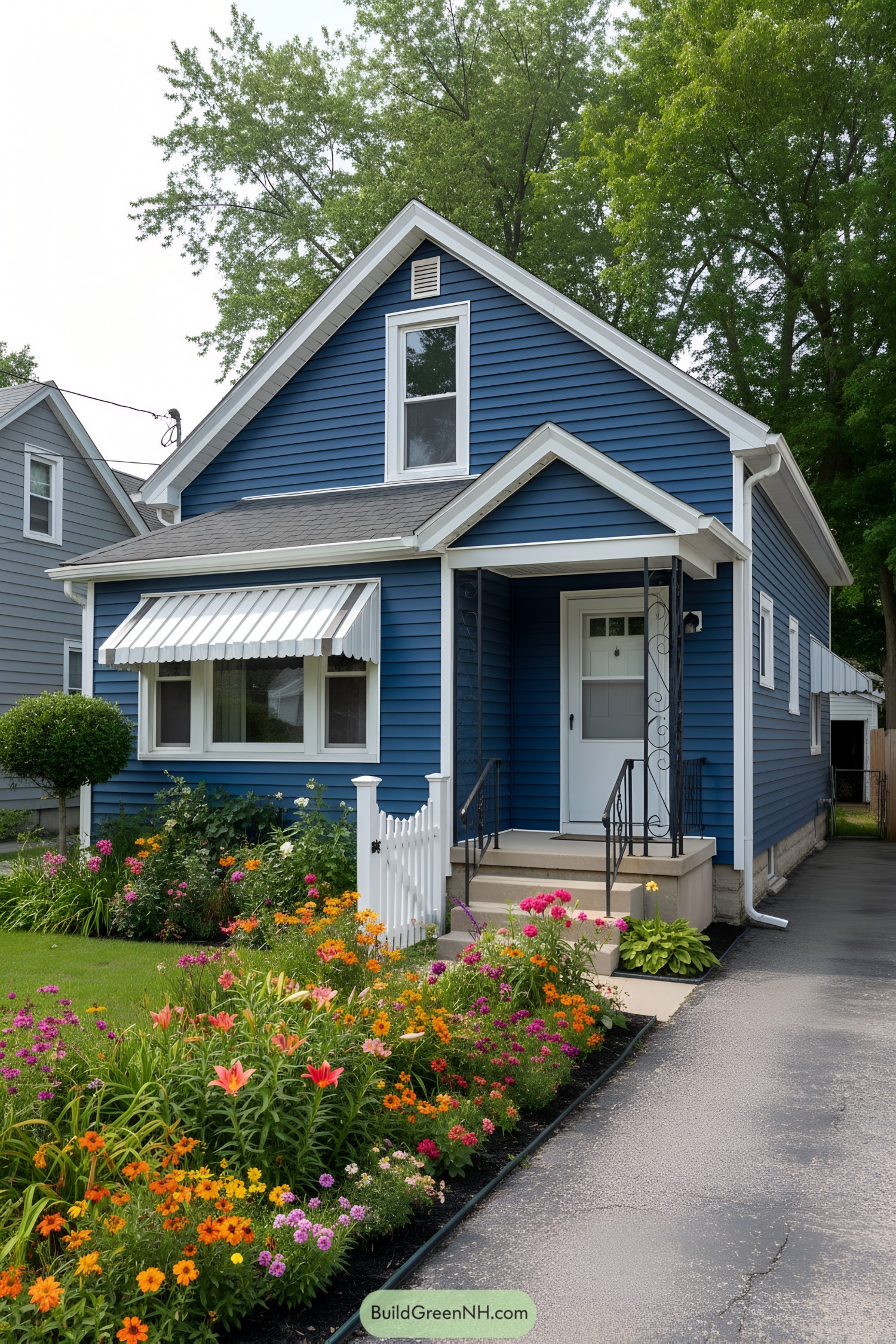 Small blue cottage with white trim, striped awning, and colorful garden