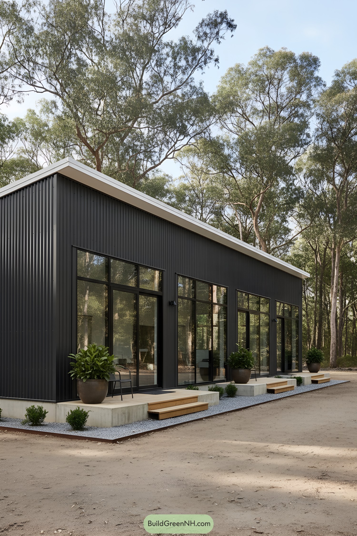 Dark metal shed with tall glass doors and small stoops along a gravel-edged slab