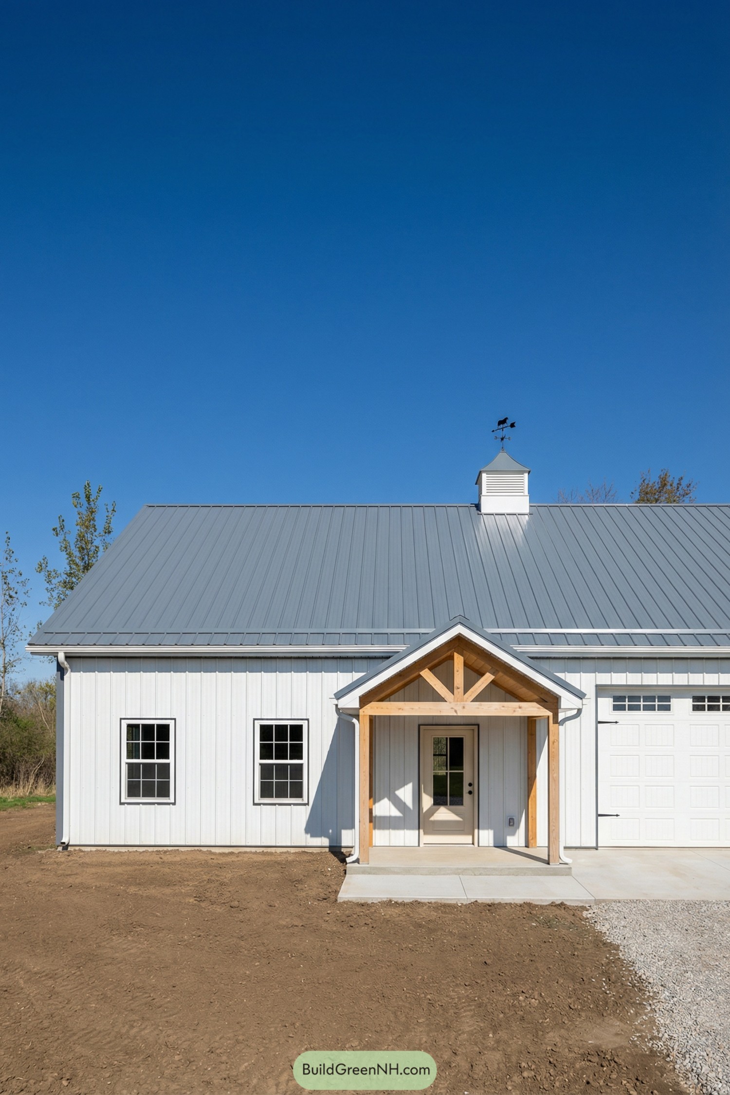 White metal barndo with gray roof and small timber porch, cupola and weathervane on ridge