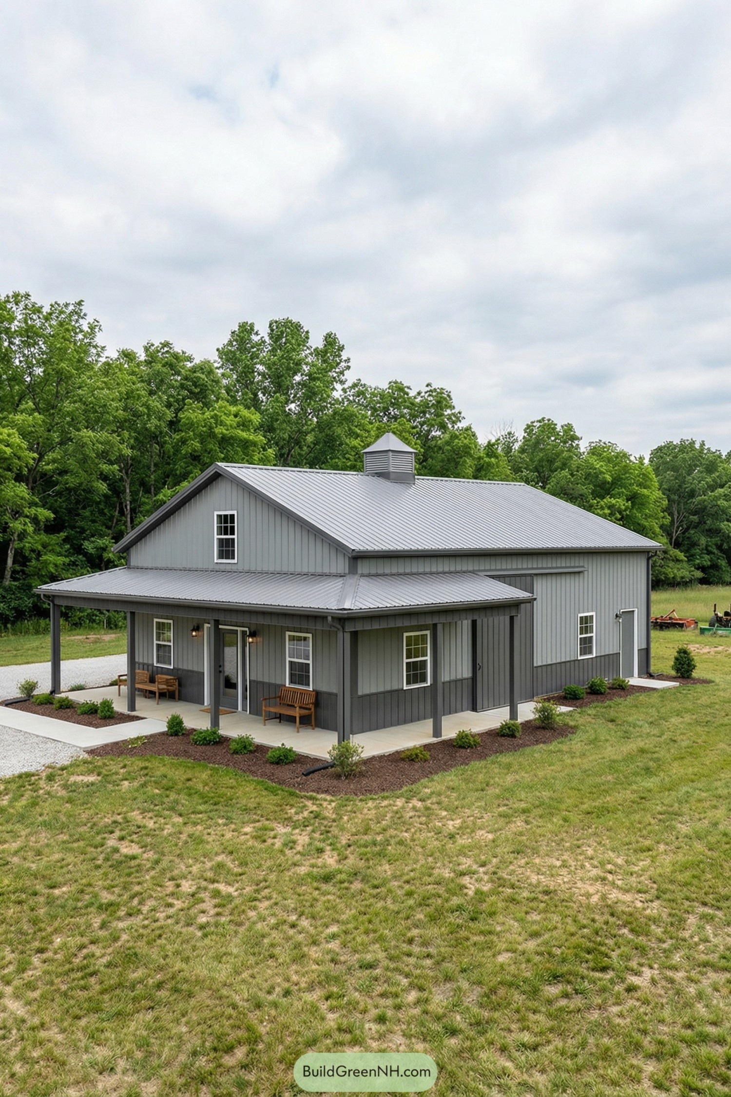 Gray metal barndominium with wraparound porch and cupola
