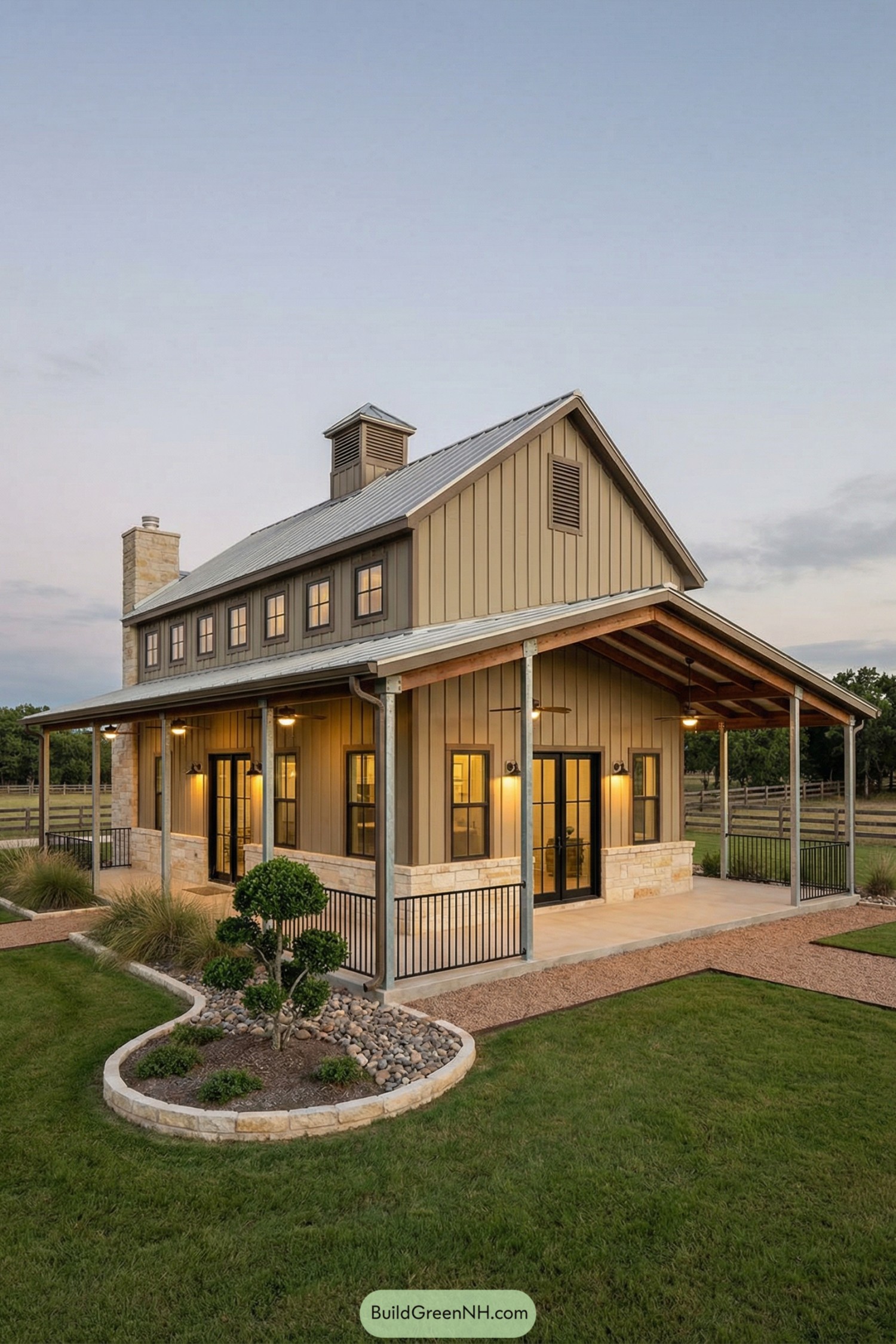 Tan metal barndo with wraparound porch and stone base at dusk