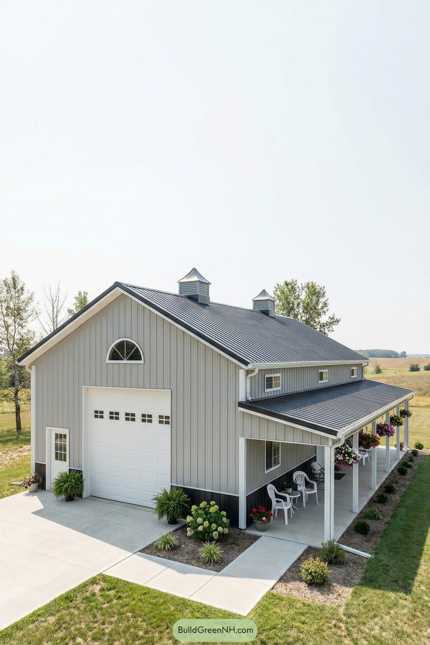 Light gray metal barn home with black roof, wraparound porch, and flower boxes