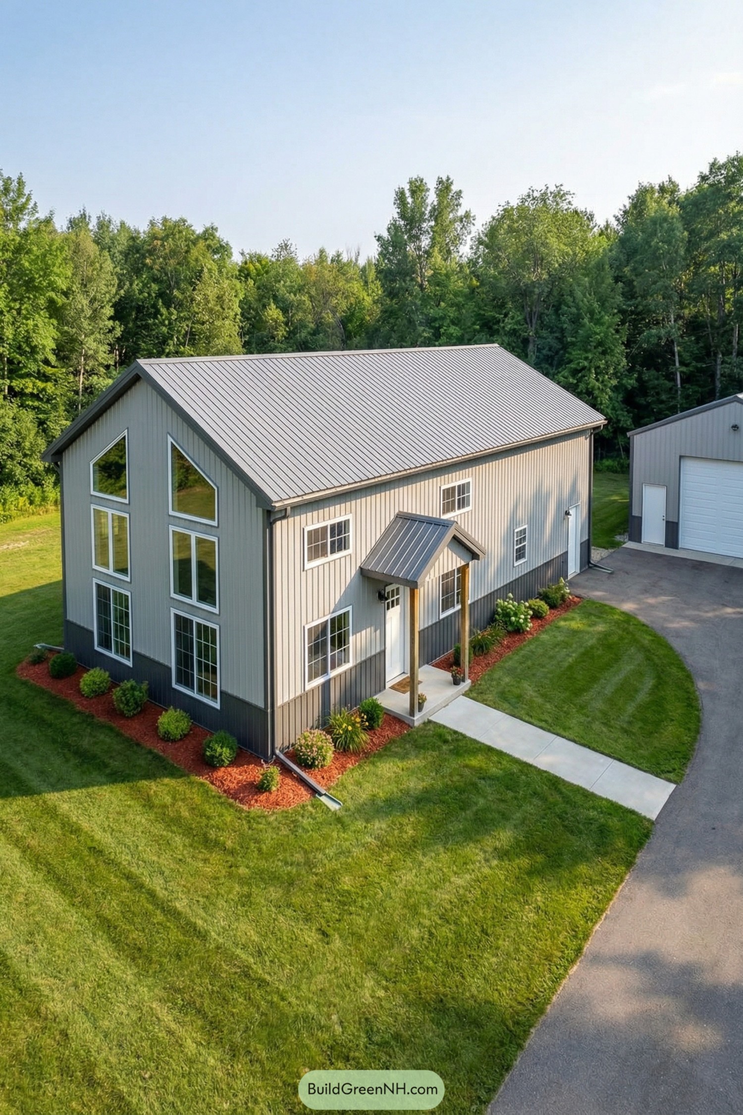 Two-story metal barndominium with large windows and a gable roof