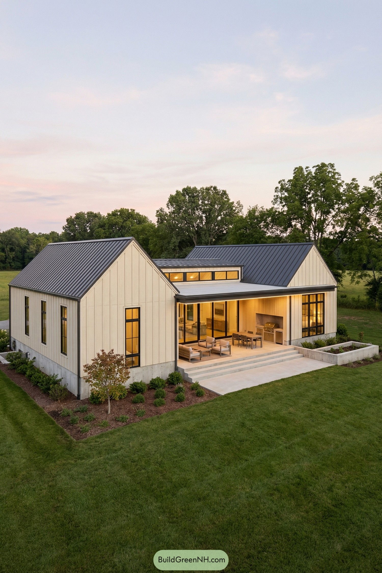 Modern cream farmhouse with dark metal roof and open patio facing a large lawn