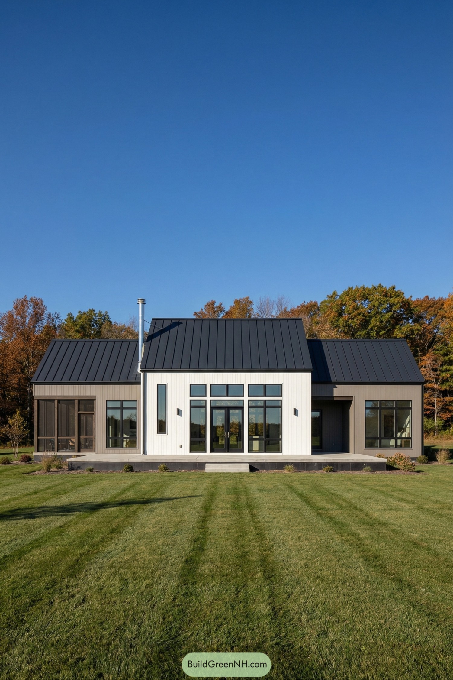Modern single-story farmhouse with black metal roof and large grid windows facing a wide lawn