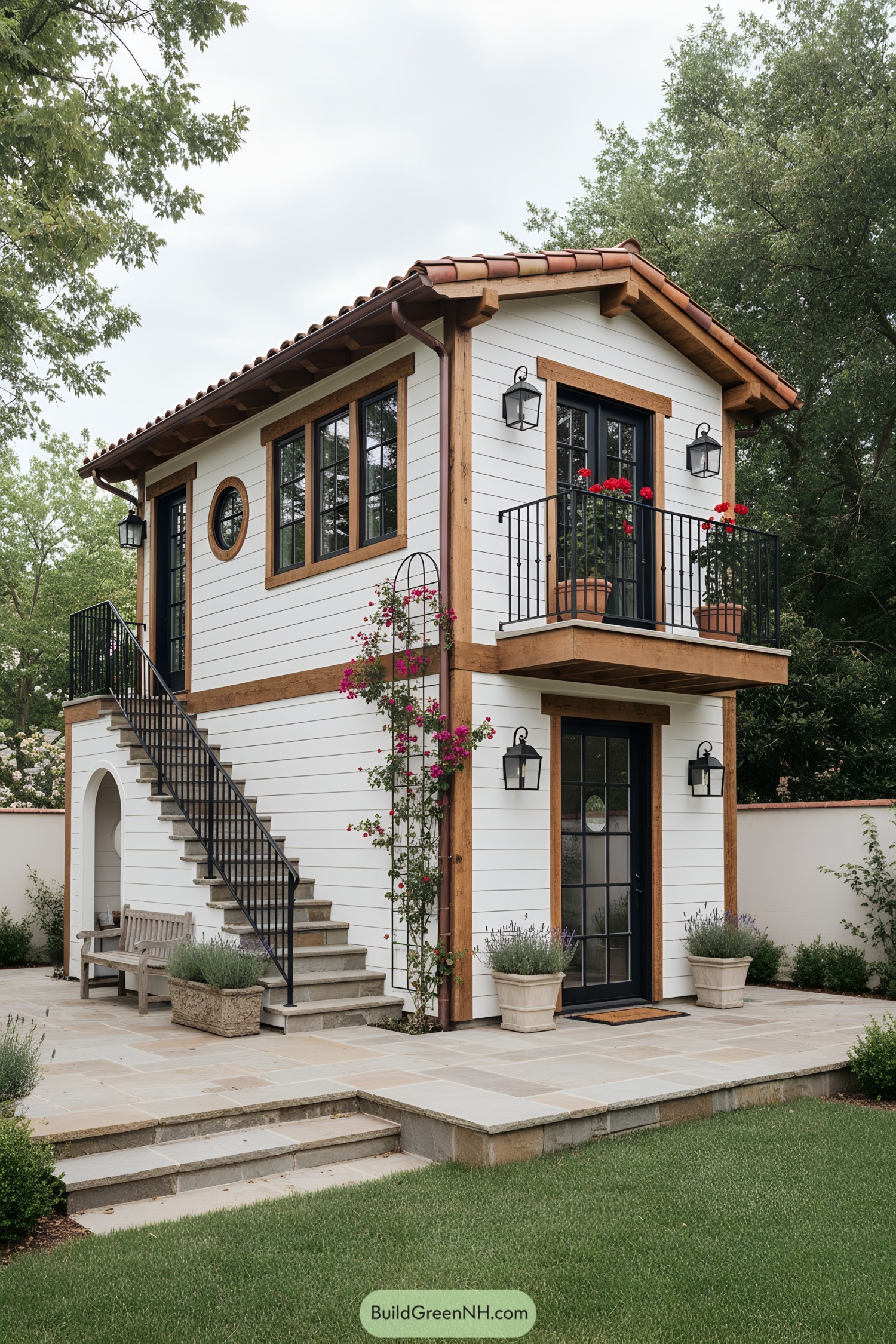 Two-story tiny house with terracotta roof, white siding, black balcony, and exterior stair