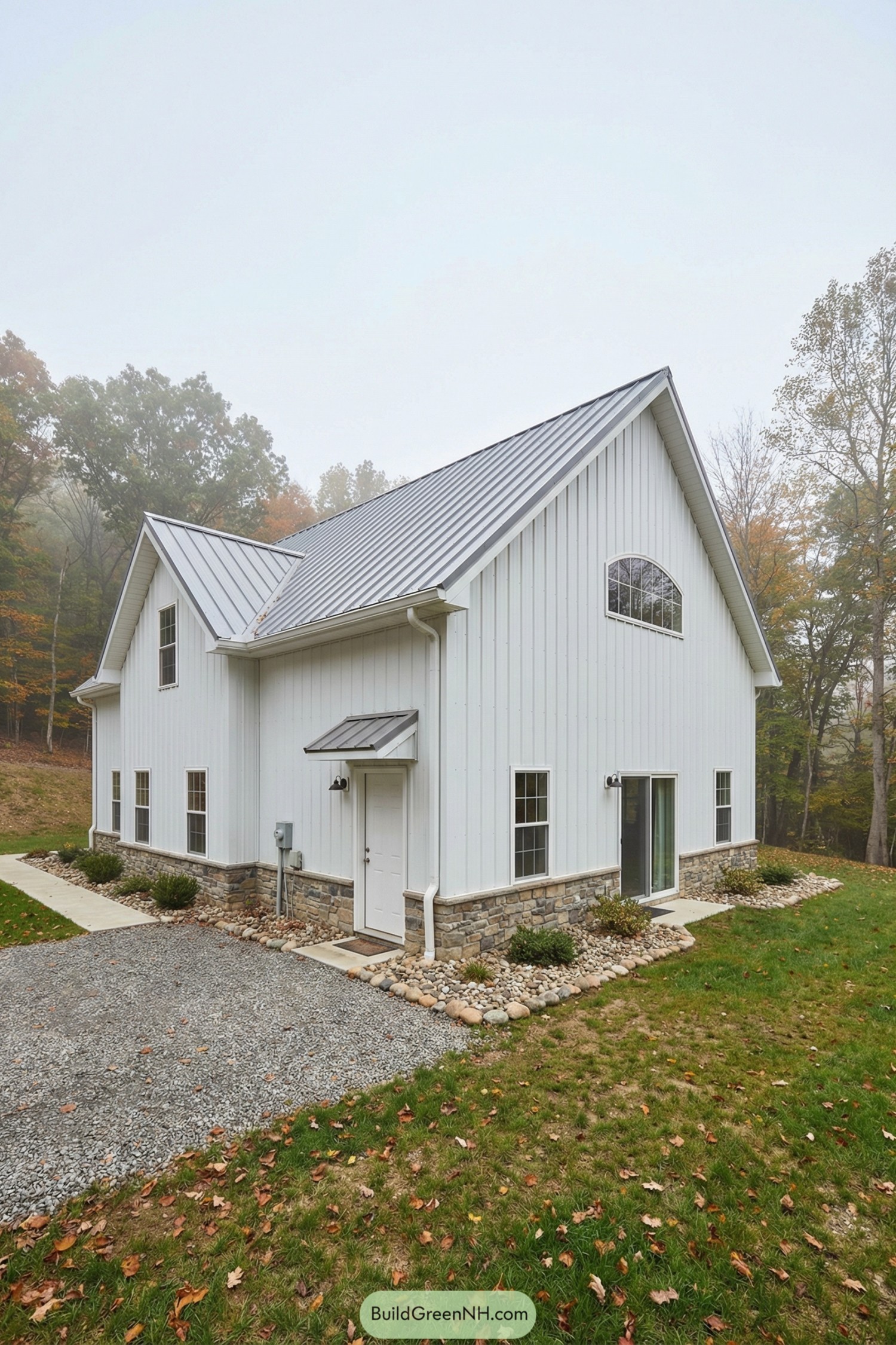 White board-and-batten barn home with metal roof and stone base