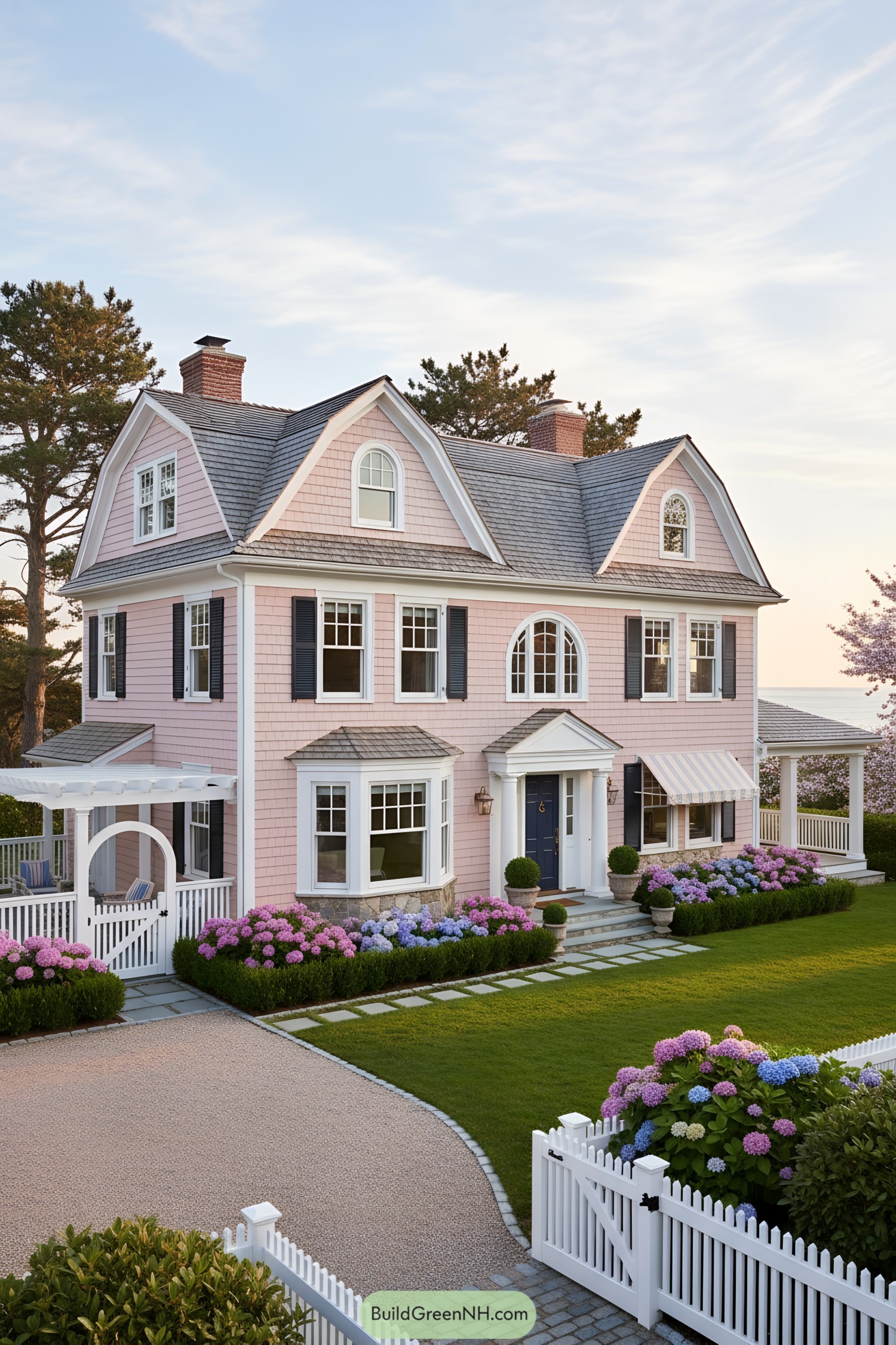Pink shingle gambrel house with navy shutters and lush hydrangeas