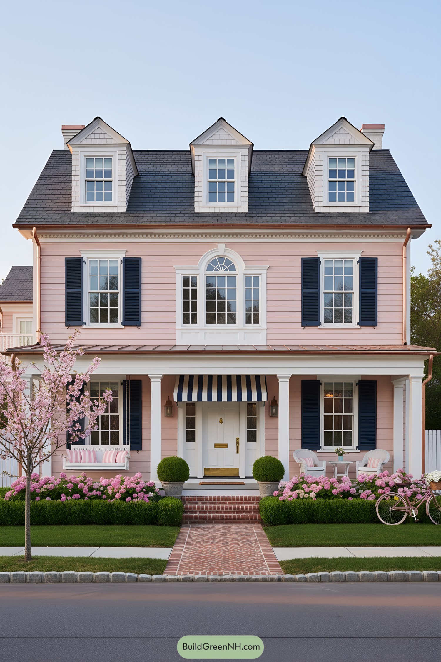 Pink clapboard house with navy shutters and striped awning