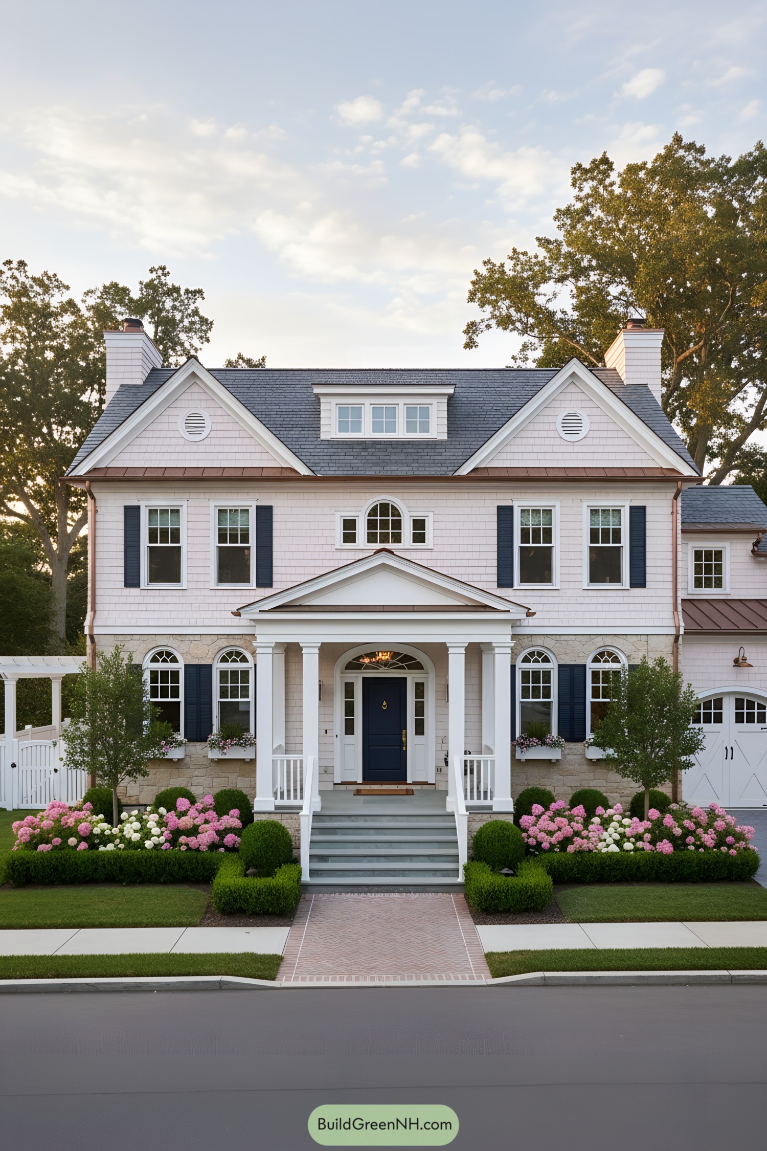 Elegant white colonial with navy door and shutters, gabled roof, and manicured hydrangeas in front
