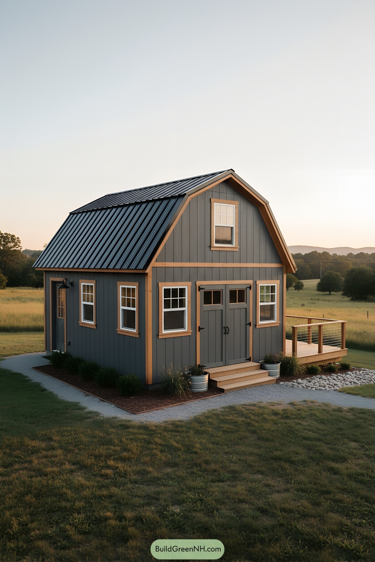 Gray gambrel-roof shed with loft and side deck at sunset