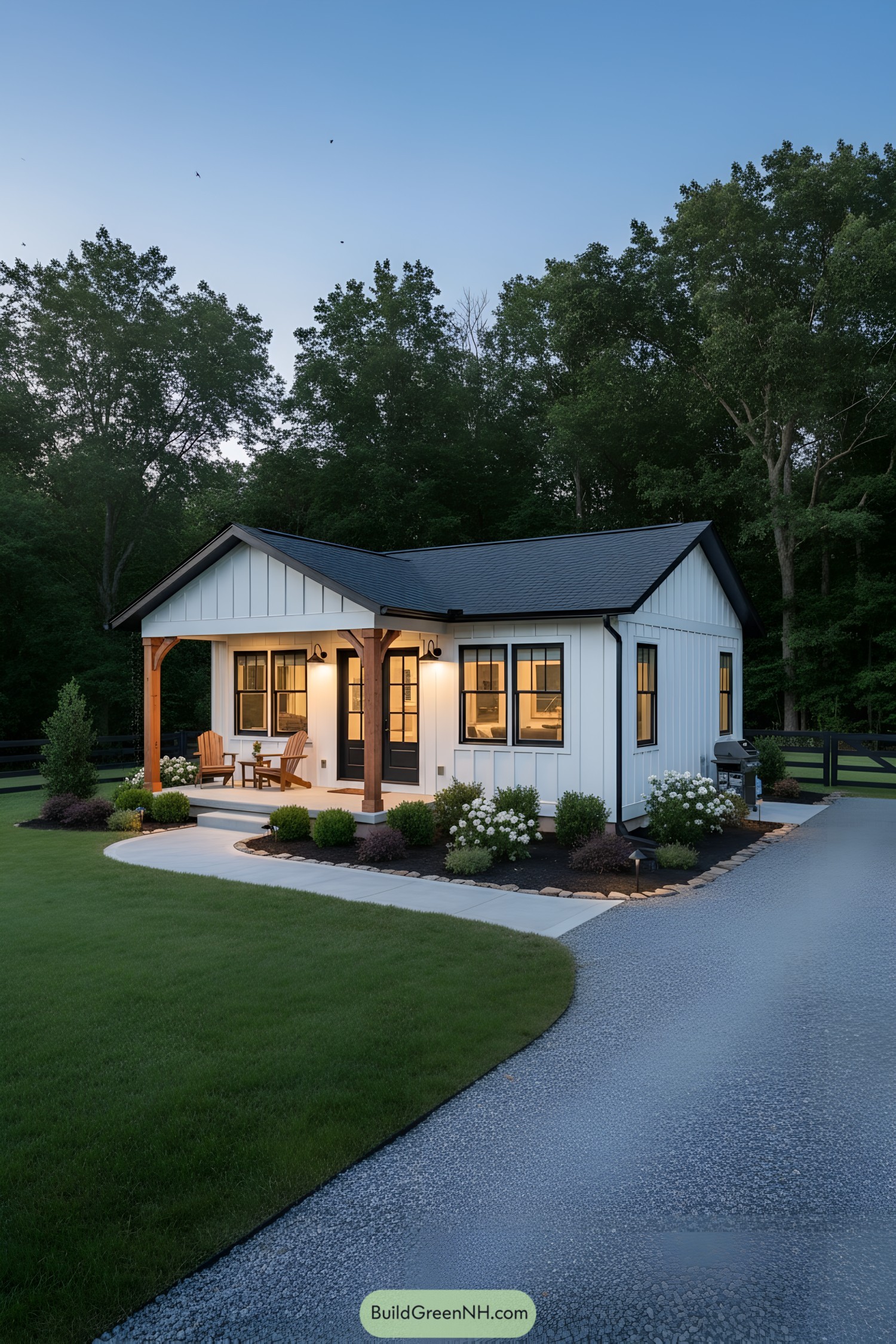 Small white board-and-batten ranch with warm porch lights, cedar posts, and black-trim windows beside a curved path