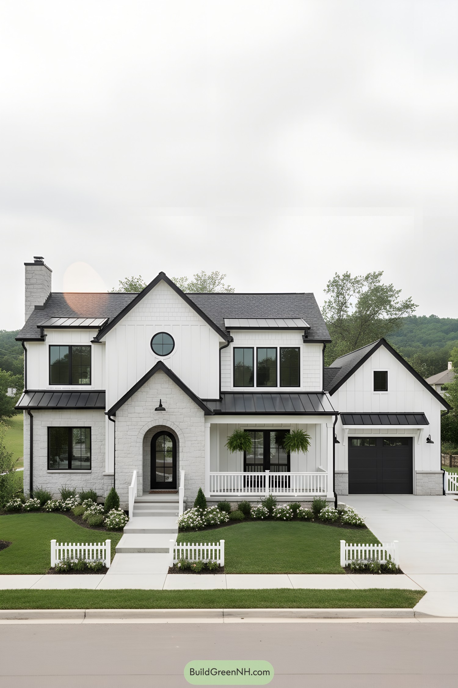White farmhouse with black metal roofs, arched entry, round window, and attached garage