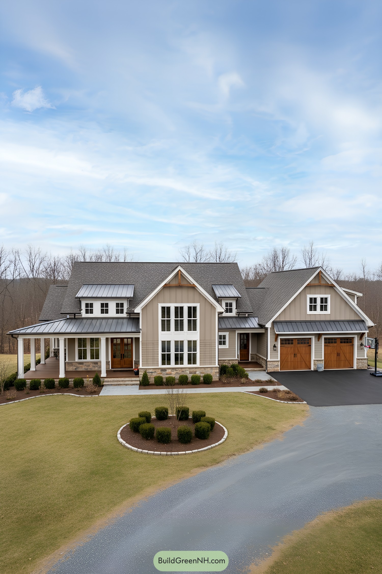 high-res photo of suburban farmhouse, modern farmhouse facade with symmetrical central gable and layered wings, wraparound porch, mixed board-and-batten and horizontal lap siding, earthy taupe and sage-gray palette with white trim; large, multi-gabled, L-shaped structure with attached garage wing; materials: painted fiber-cement siding, natural stone base accents, exposed timber brackets, dark metal porch roof elements; roofing: dark gray architectural shingles with shed metal roof sections over porch and dormers; windows: white-framed double-hung and fixed grids, tall triple-stacked mullions at central bay, small dormer windows; doors: stained wood double entry with glass panels, carriage-style wooden garage doors with X-bracing and black hardware; outdoor area: deep covered porch with square tapered columns, side veranda, gravel circular drive, basketball hoop near garage; landscaping: manicured boxwood hedges, low shrubs, mulched beds, minimal stone edging; surrounding background: open lawn, sparse leafless trees, distant woodland under soft blue sky with scattered clouds. ultra-realistic, high-resolution, architectural photography, soft lighting, cinematic composition