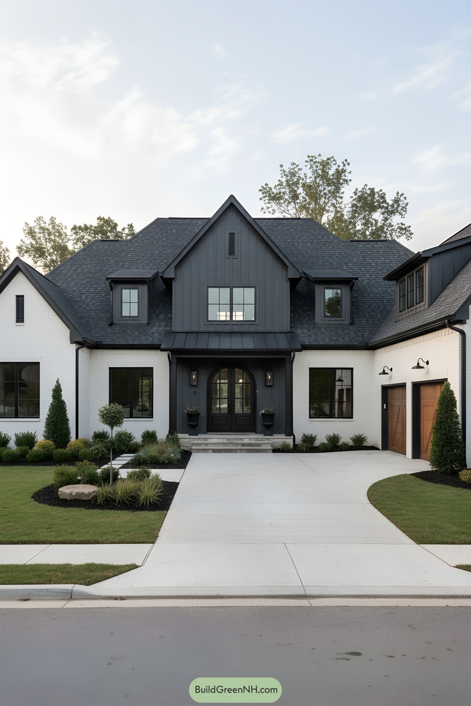 Black and white gabled farmhouse with arched door and wood garage doors