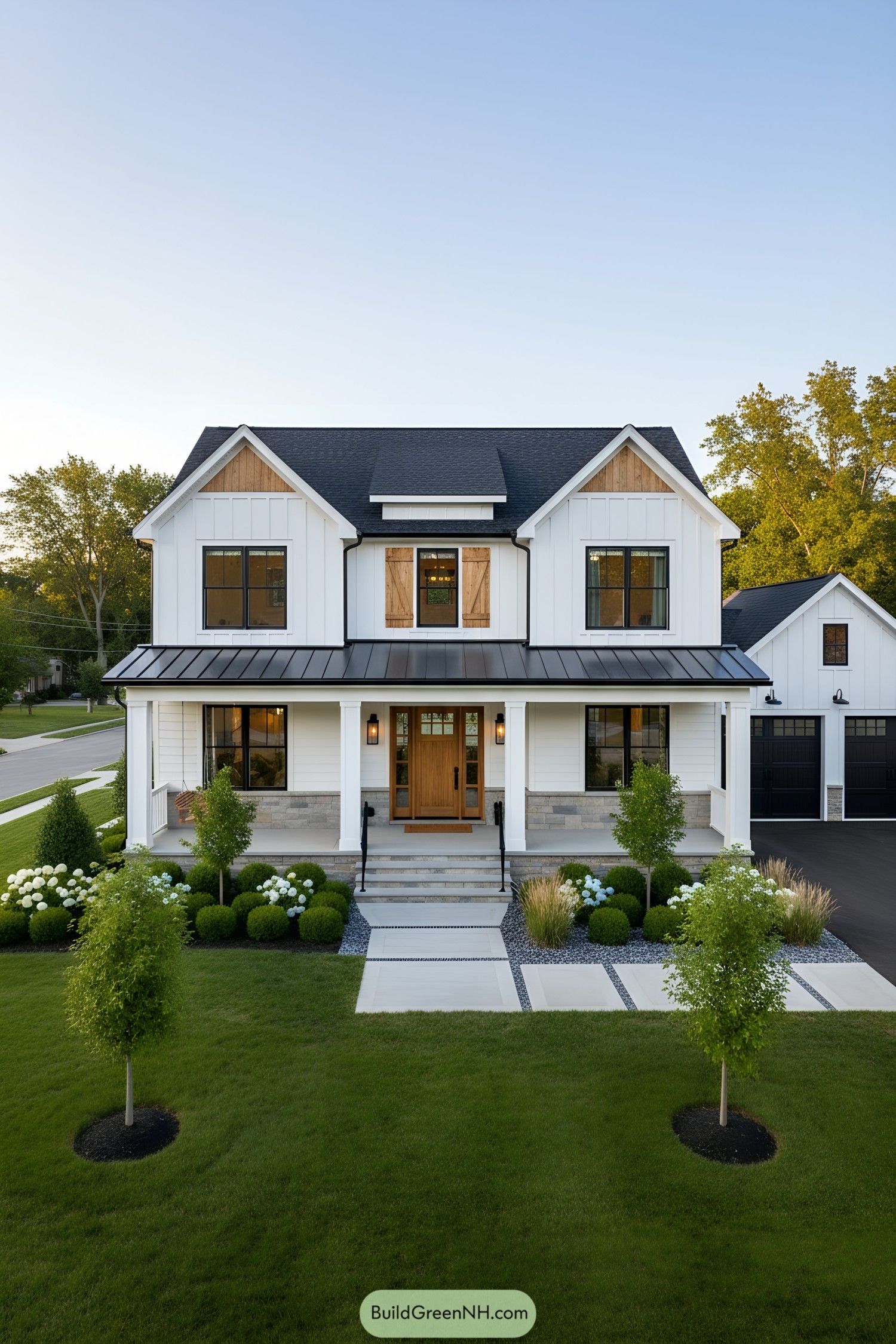 White farmhouse with black metal accents, warm wood door, gabled roof, and manicured front garden