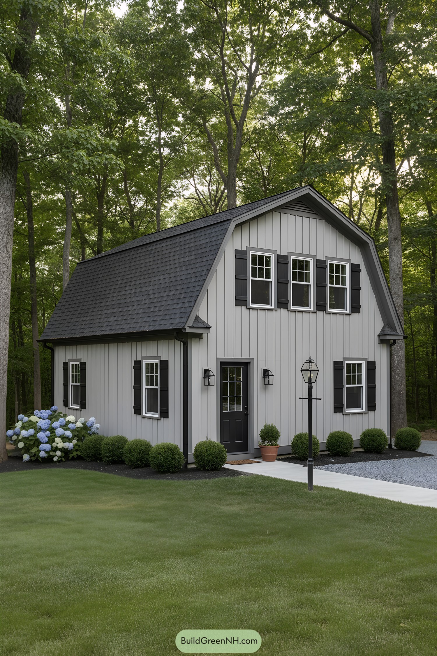 Compact gray gambrel tiny house with black shutters and trim