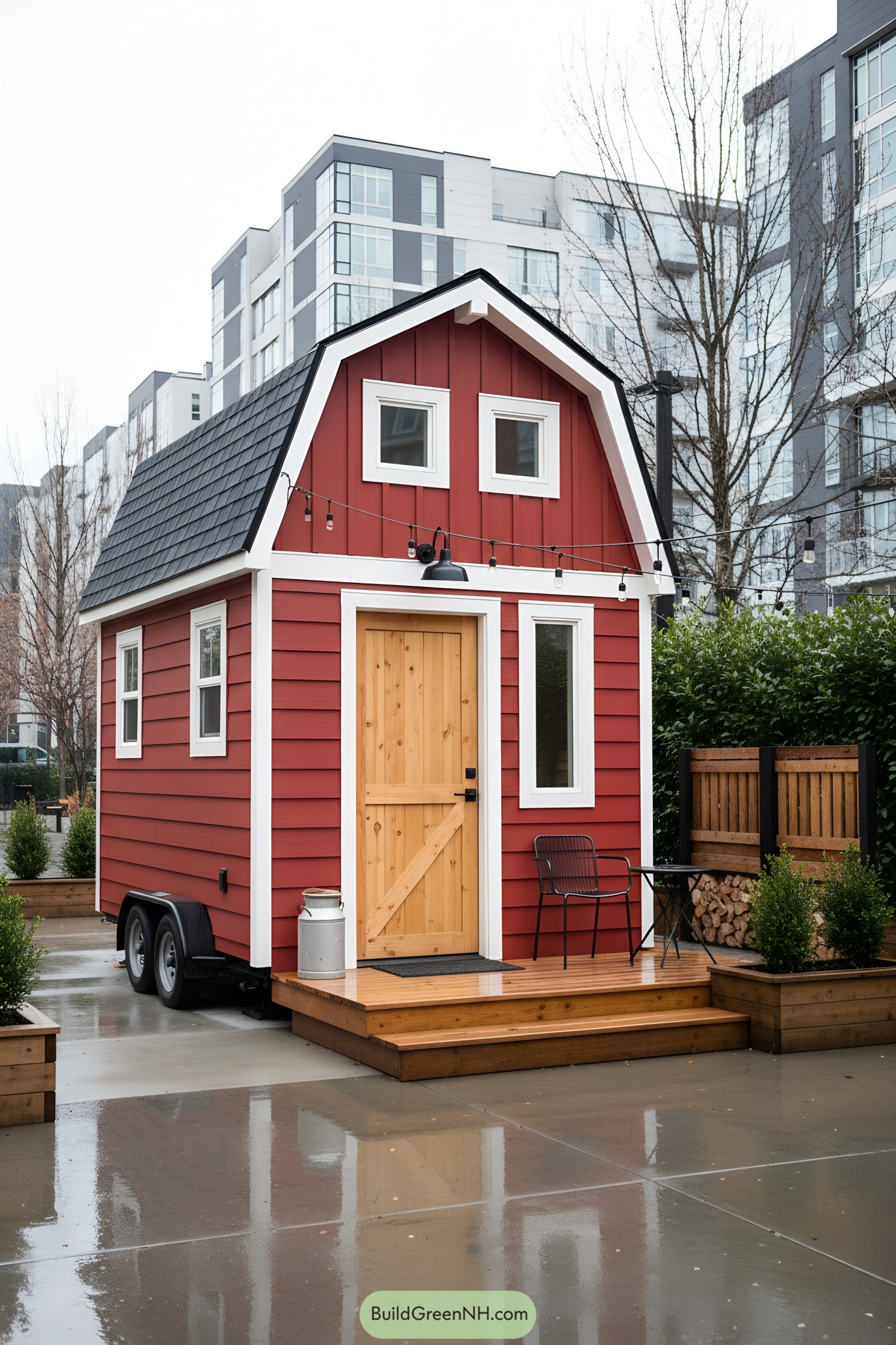 Red tiny barn house with gambrel roof and wood door on a small deck