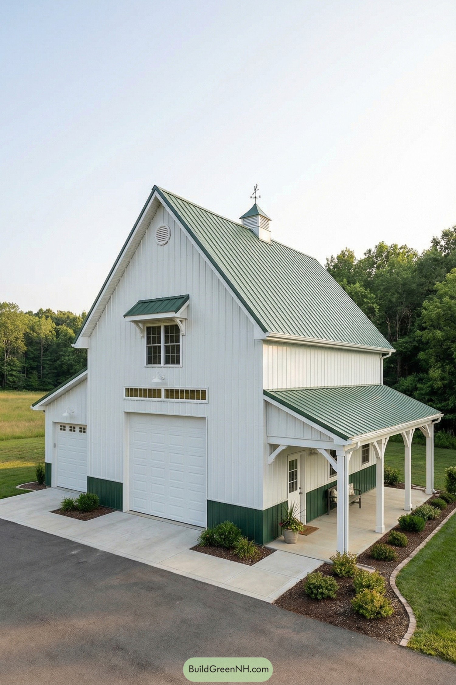 White pole barn with green metal roof, cupola, porch, and large garage doors