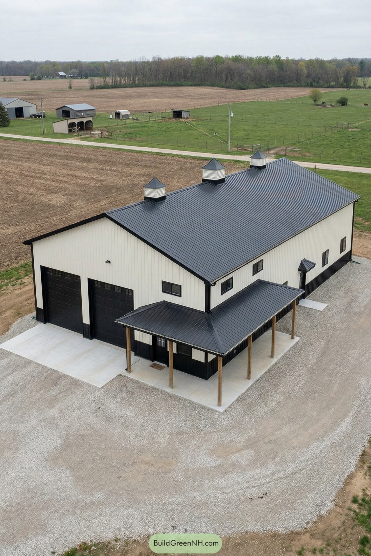White pole barn with black roof and wraparound porch