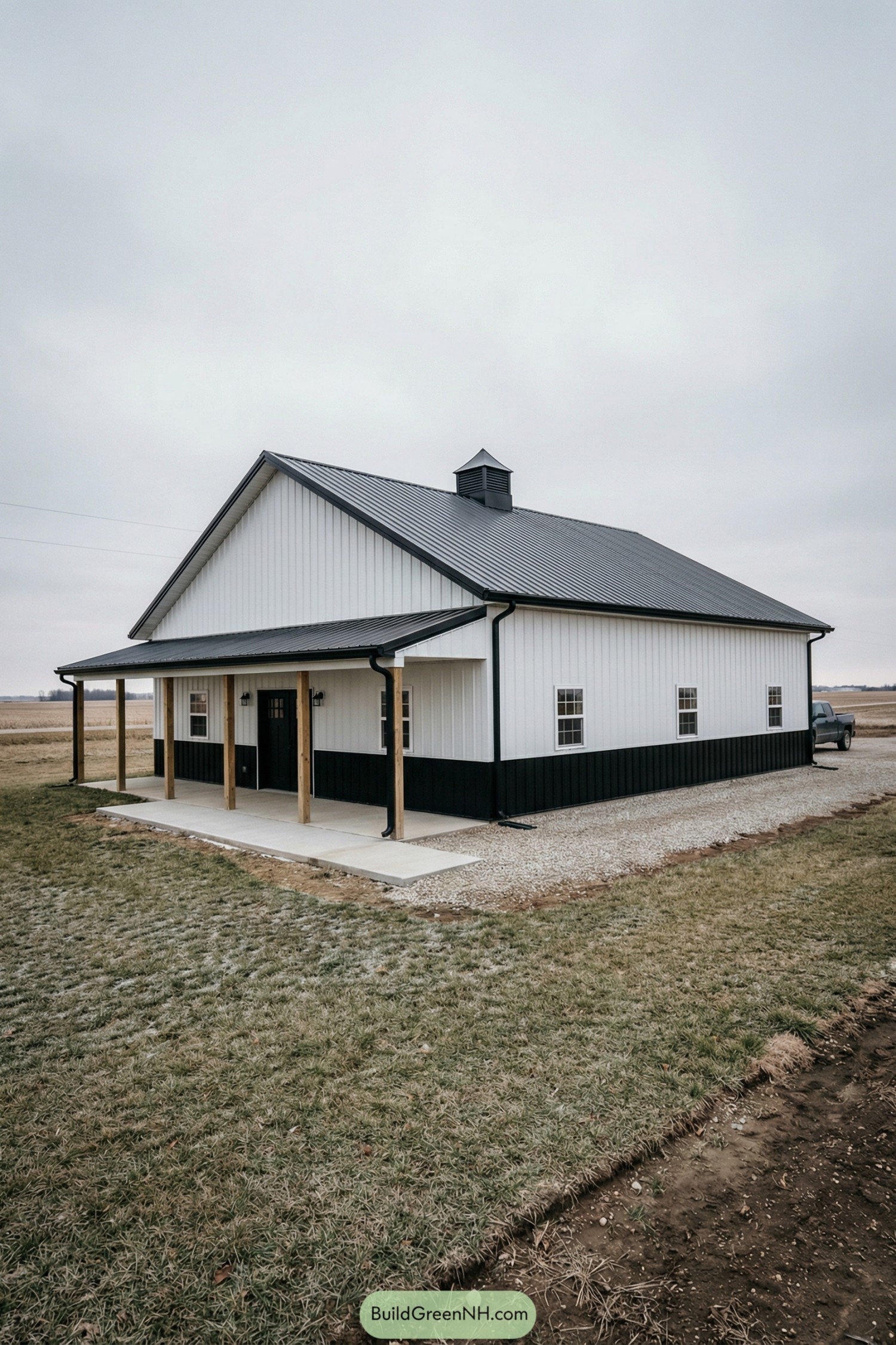 White pole barn house with black wainscot, metal roof, and small porch with timber posts
