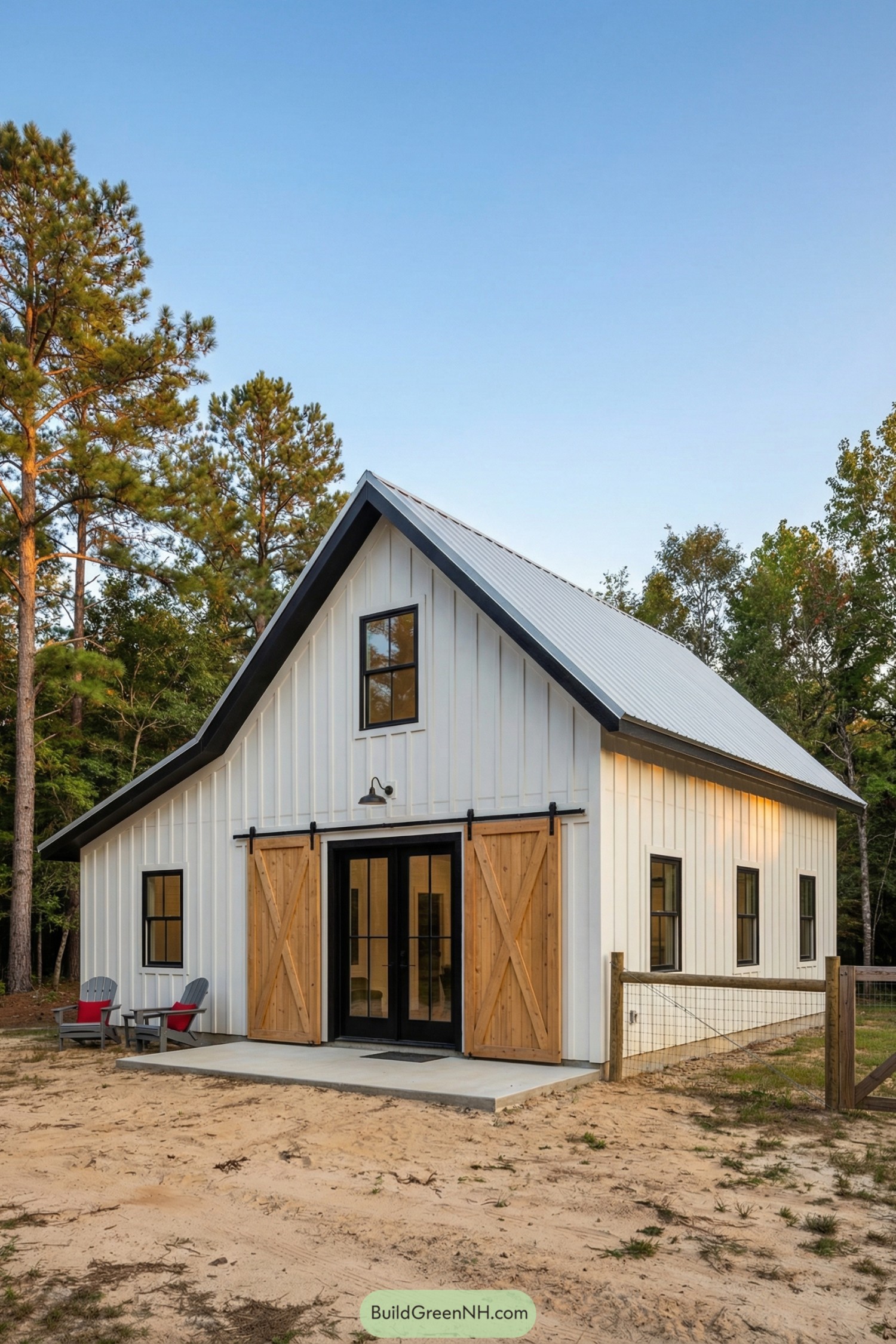 White board-and-batten barnhouse with black trim, metal roof, and twin cedar sliding doors